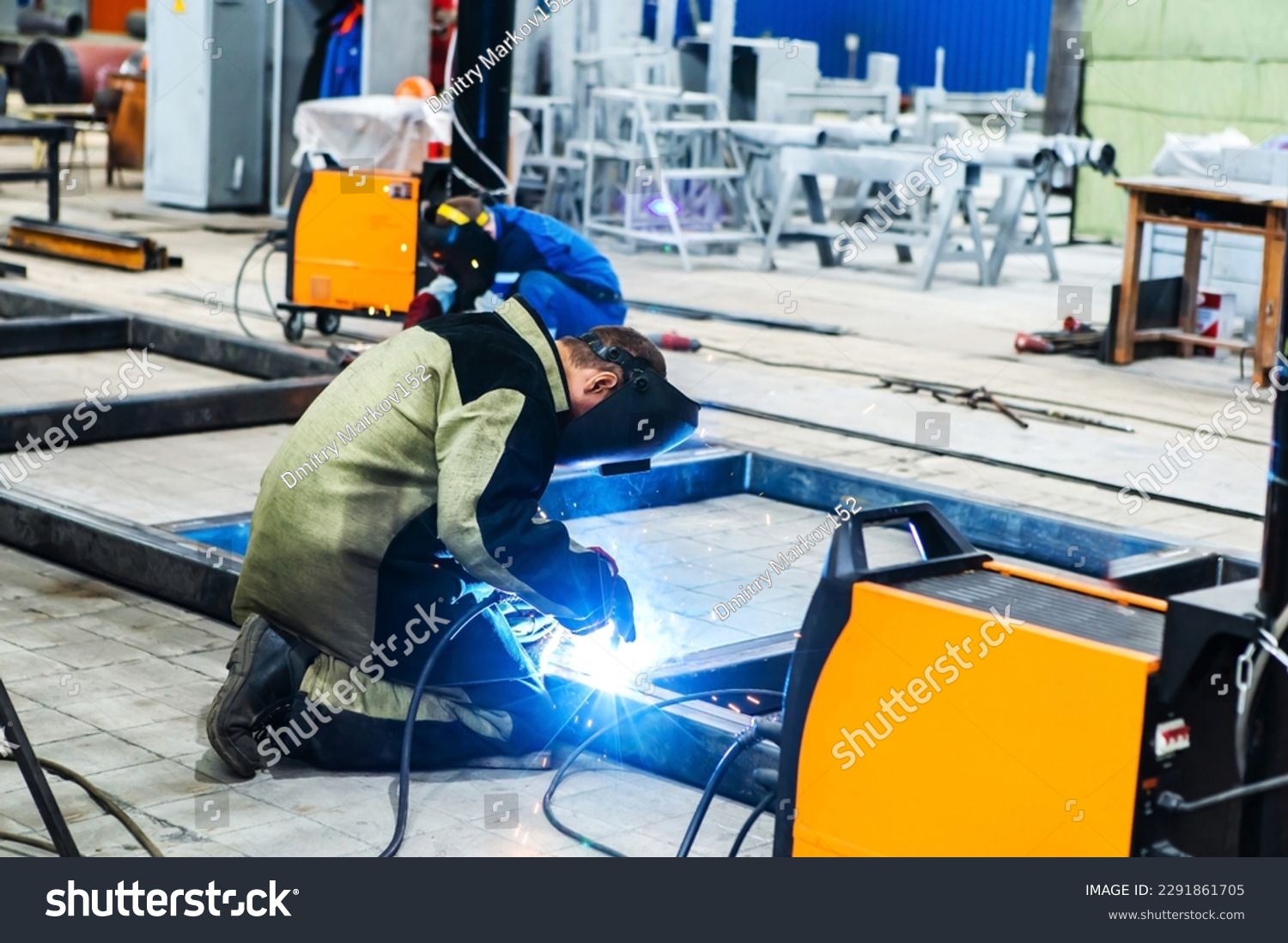 An electric welder works at an industrial enterprise. The process of welding a metal structure from a metal profile. Unrecognizable person. Foreground #2291861705