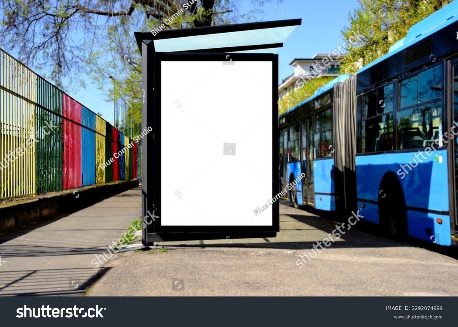 bus shelter at bus stop. white poster and commercial ad space display lightbox. base for mockup. outdoors image. blank ad panel. glass design. urban street setting. green background with spring trees #2292074999