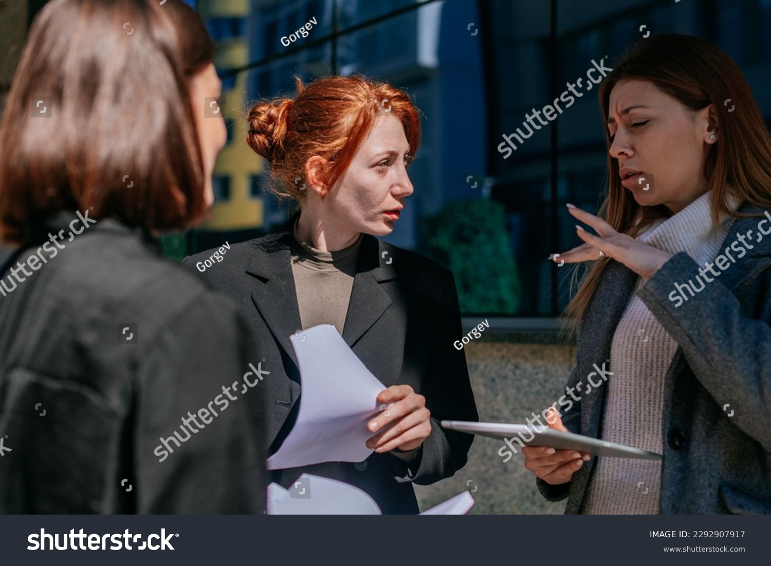 A shot of blonde businesswoman gesticulating with her hand while explaining a project problem solution to her colleagues. Ginger businesswoman looking at ther and listening #2292907917