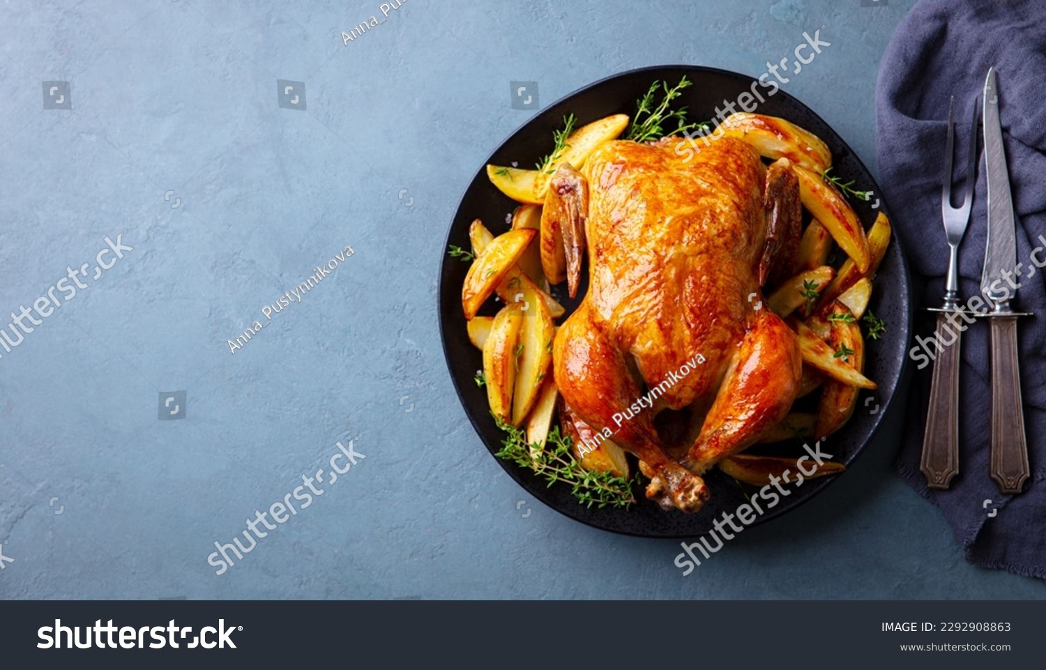 Roasted, baked chicken with potatoes and herbs on dark plate. Grey background. Copy space. Top view. #2292908863