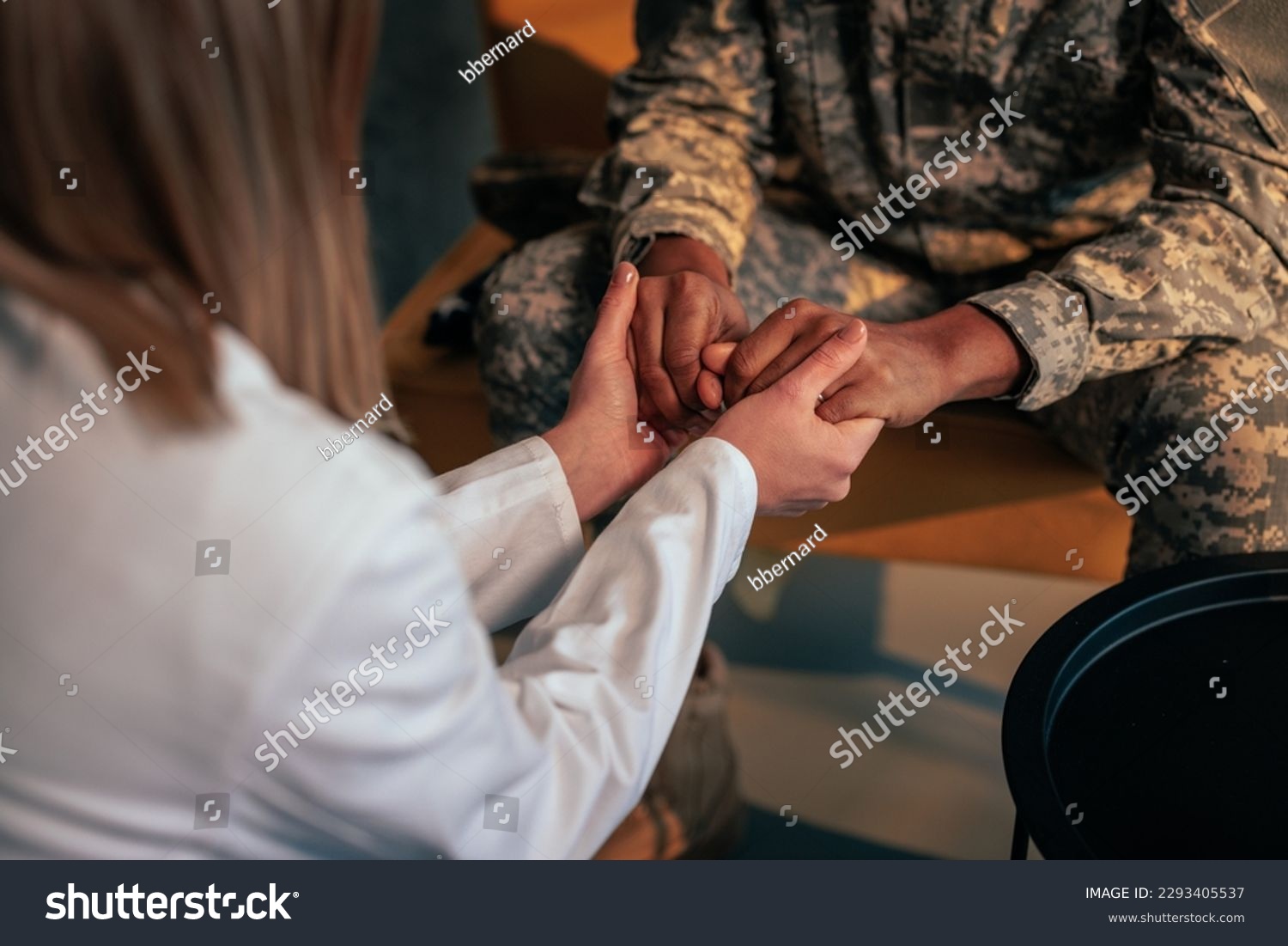 A soldier is in therapy at the psychologist office, holding hands with her in the process of rehabilitation. #2293405537
