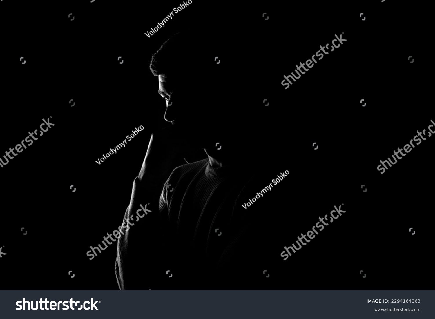 Male silhouette on a black background. A man stands thoughtfully on a black background #2294164363