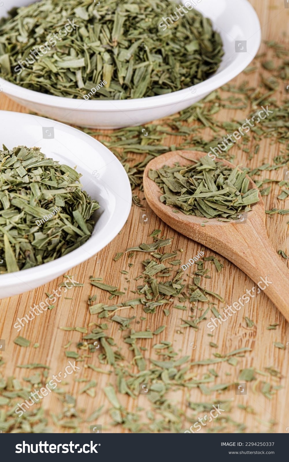 A pile of dried Tarragon Leaves isolated on a wooden cutting board with copy space #2294250337