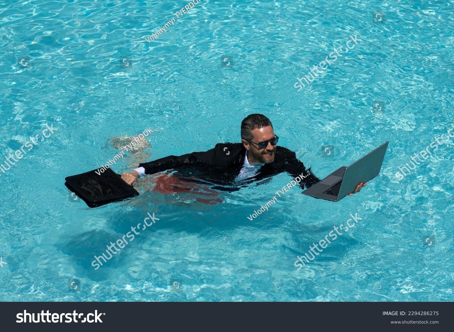 Businessman in suit with laptop in swimming pool. Crazy business man on summer vacation. Excited businessman in wet suit in swim pool. Funny business man, crazy comic business concept. Remote working. #2294286275