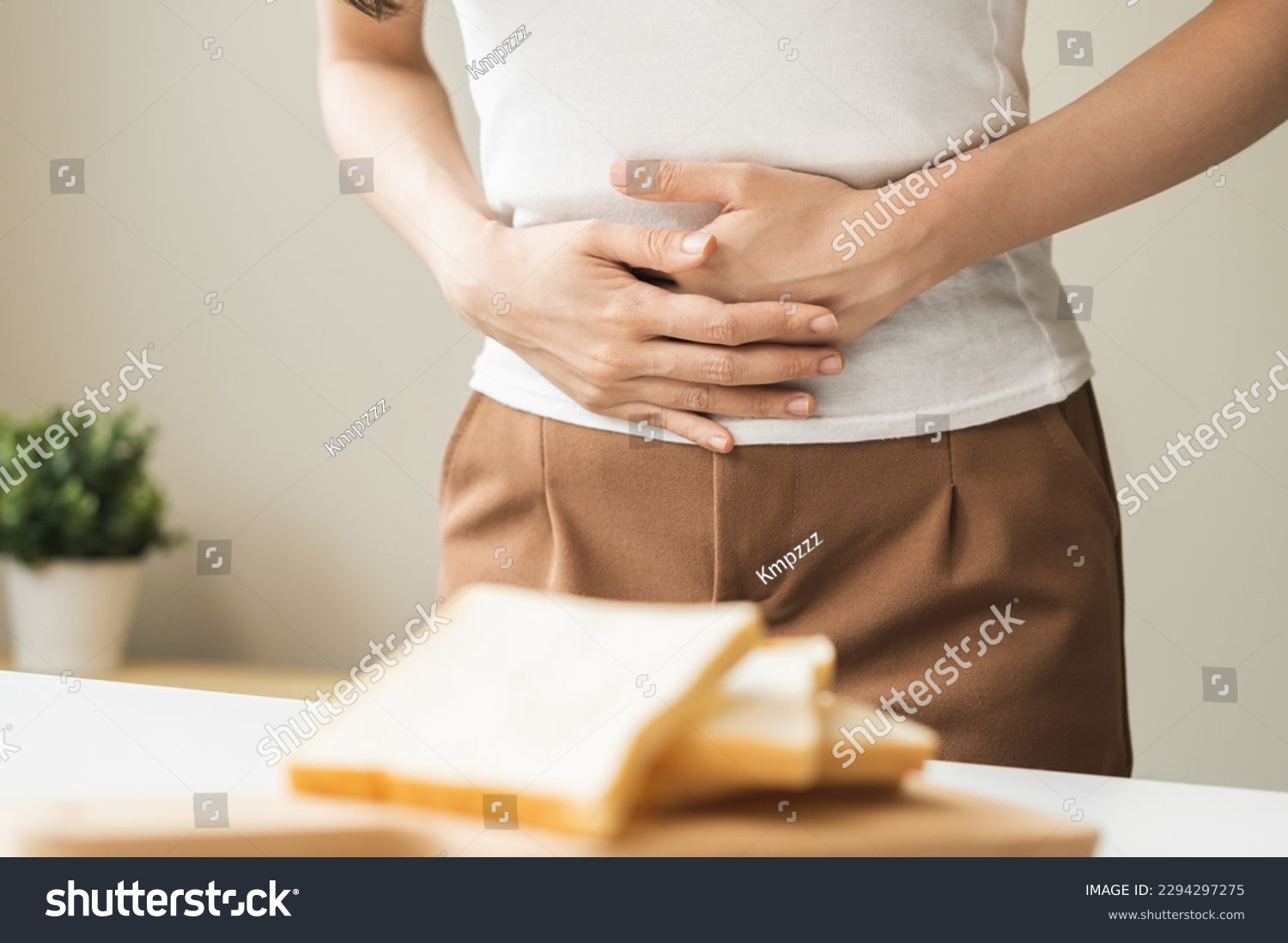Gluten allergy, asian young woman hand holding, refusing to eat white bread slice on plate in breakfast food meal at home, girl having a stomach ache. Gluten intolerant and Gluten free diet concept. #2294297275