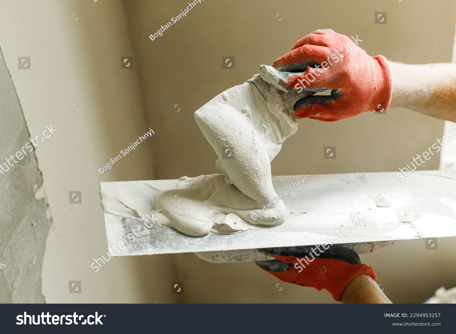 Worker plastering walls with gypsum plaster and spatula . Construction of house and home renovation concept. Close up of stucco and handyman hands with trowel #2294953257
