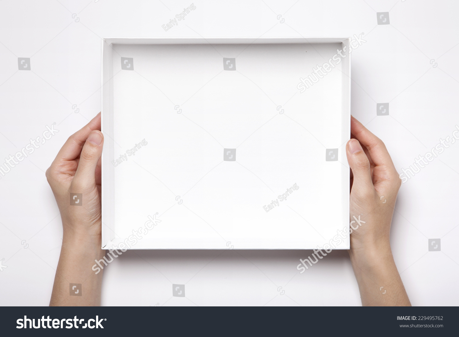 A female(woman, girl) two hands hold the empty(blank) white box isolated white, top view at the studio. #229495762