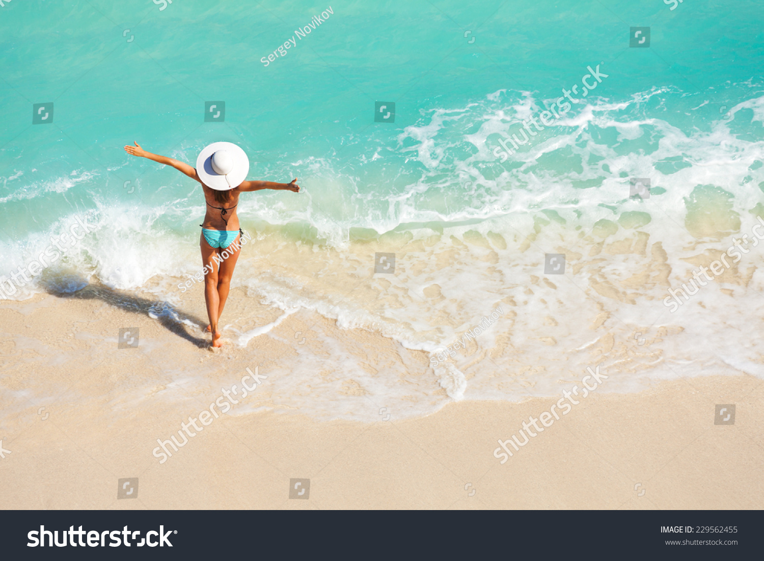 Young woman with arms apart on sand beach #229562455