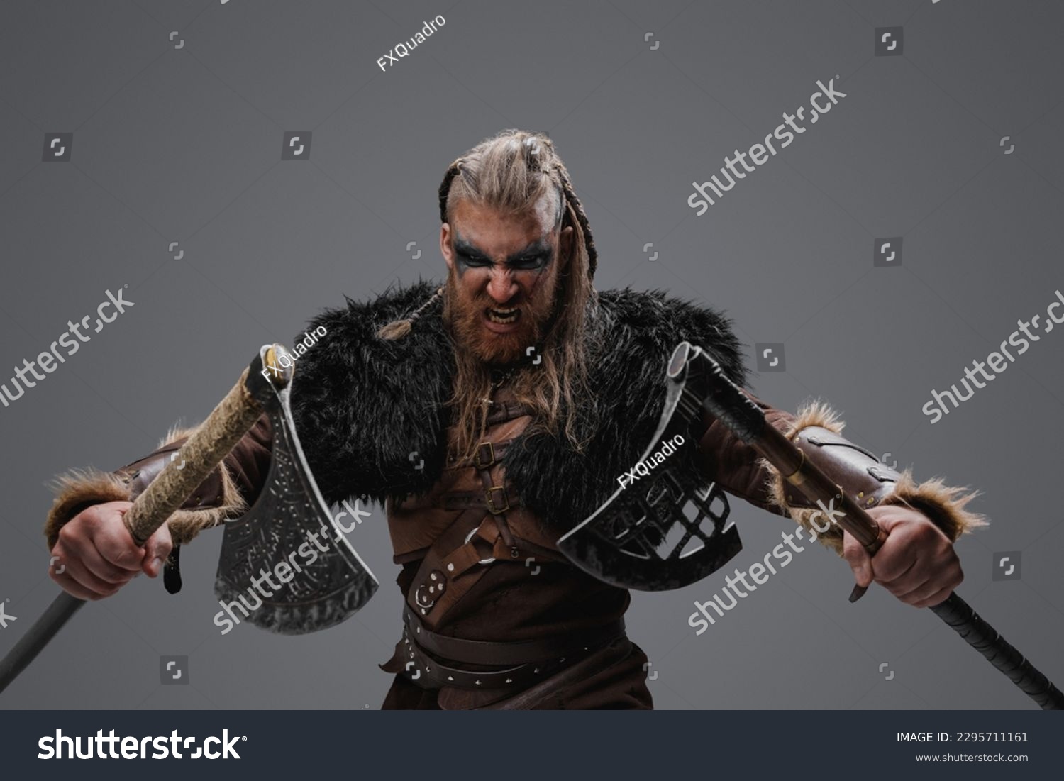 Portrait of fierce viking from past with dual axes against gray background. #2295711161