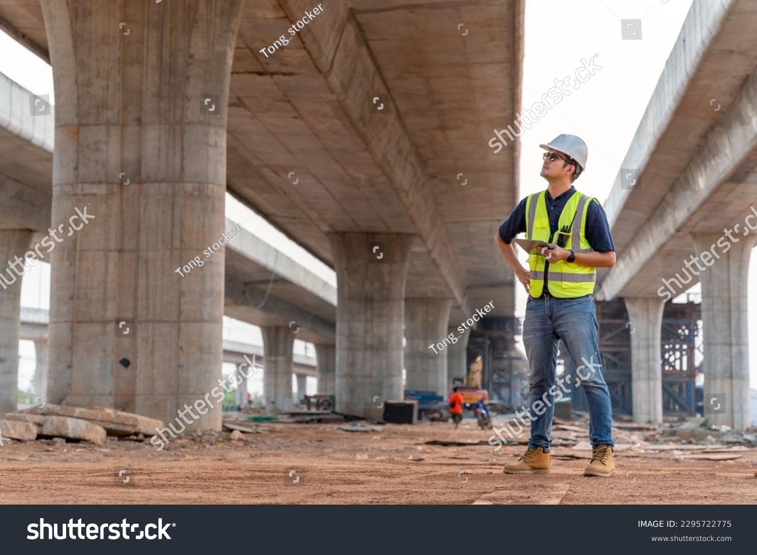 A civil engineer is inspecting a road or expressway construction project under a road under construction. #2295722775