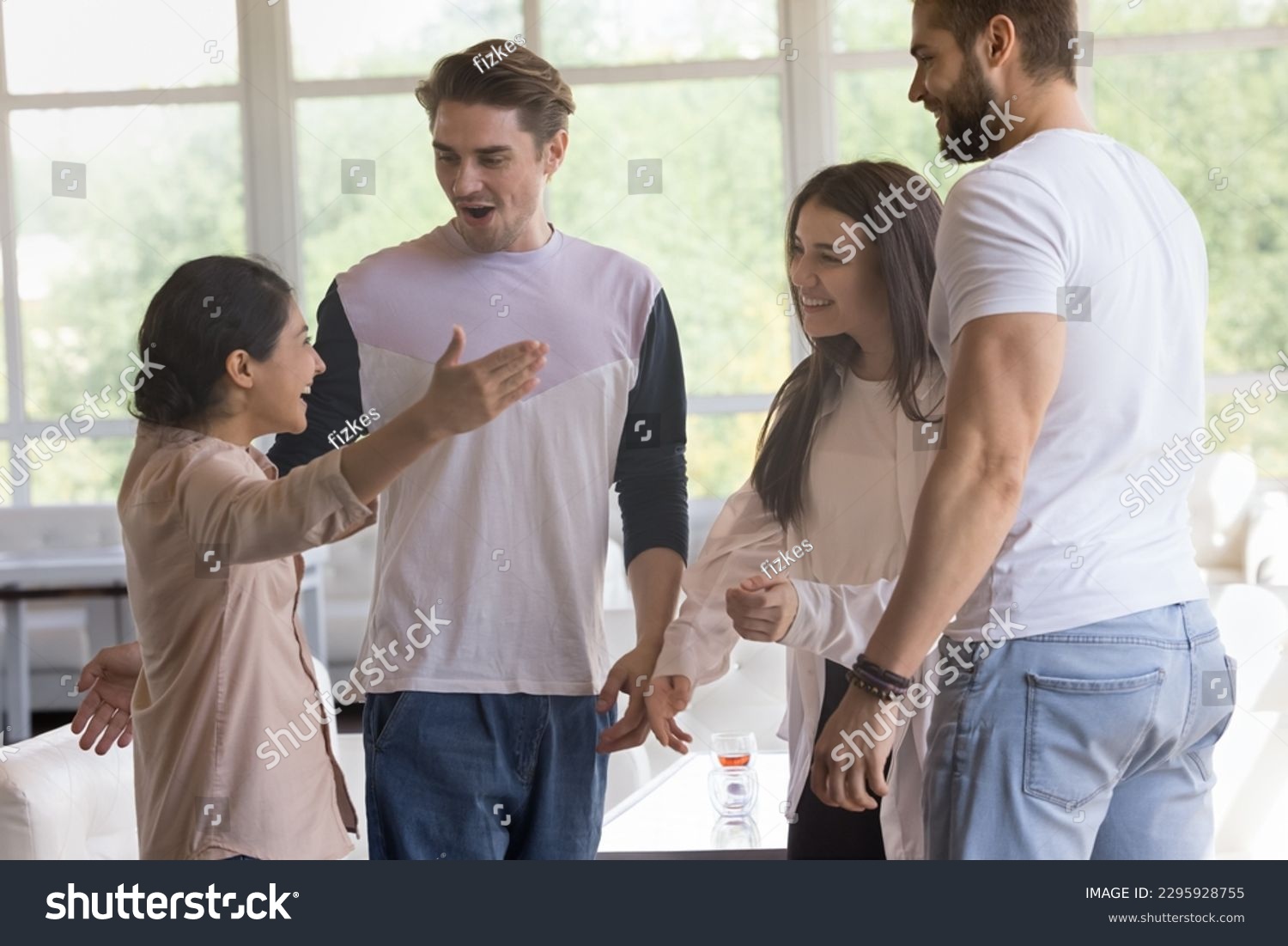 Indian woman greets best friends meet in modern cafe, looks surprised welcoming, hugging guys and girl, stand together, enjoy friendship gather in public place, express warmth and friendly relations #2295928755