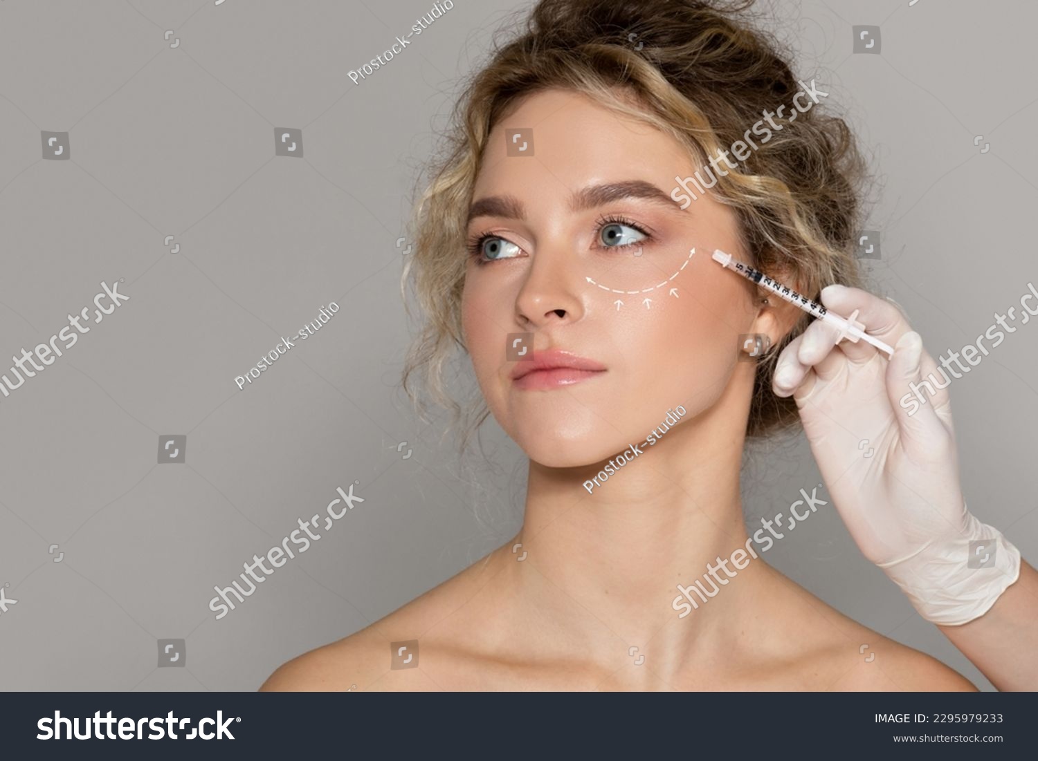 Beautician doctor making injection to young beautiful woman with drawn line under eye, lady with perfect smooth skin getting mesotherapy treatment or hyaluronic acid shot #2295979233