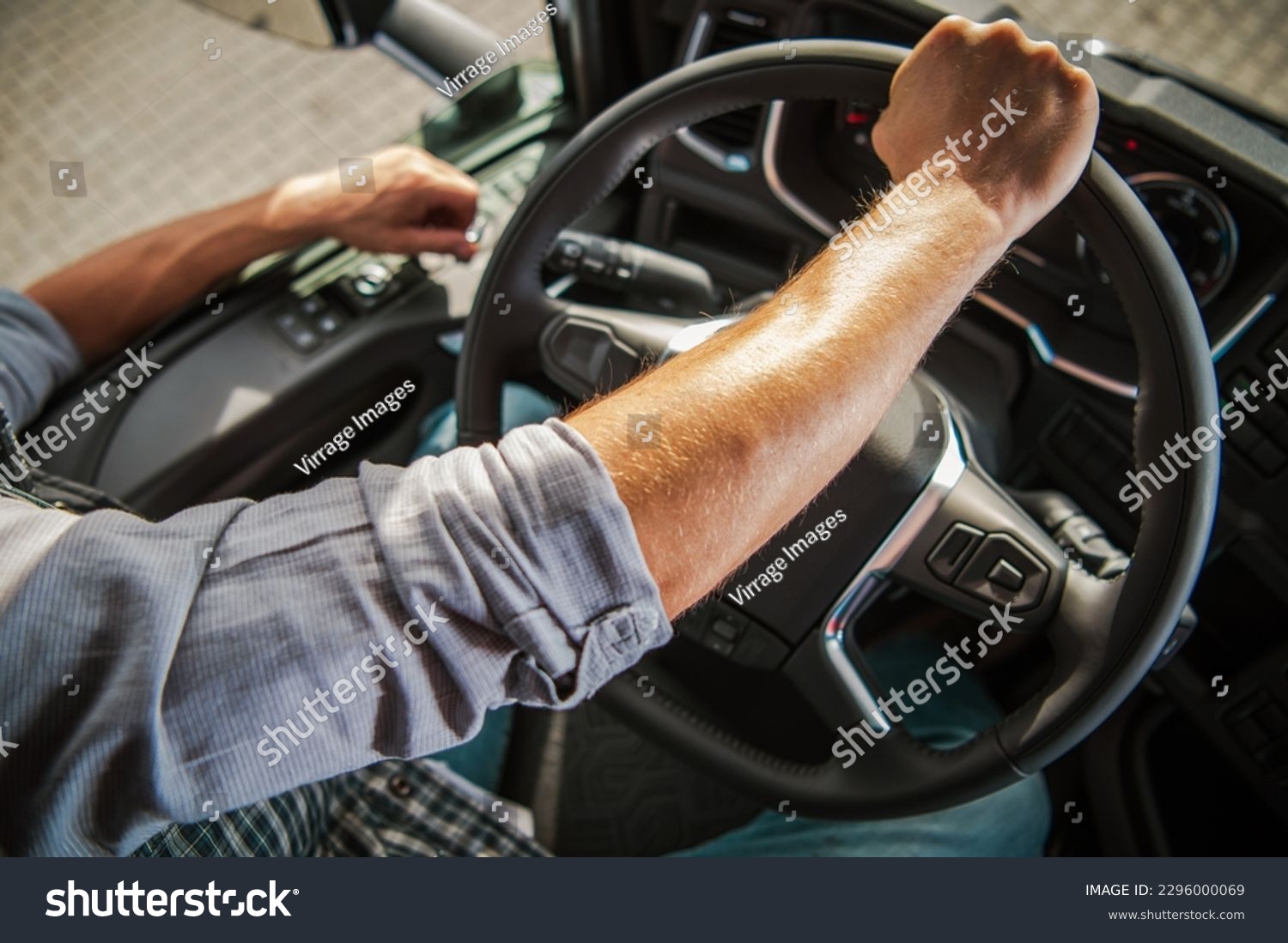 Truckers Hand on a Semi Truck Steering Wheel Close Up Photo. Caucasian Professional Driver Theme. Transportation Industry. #2296000069