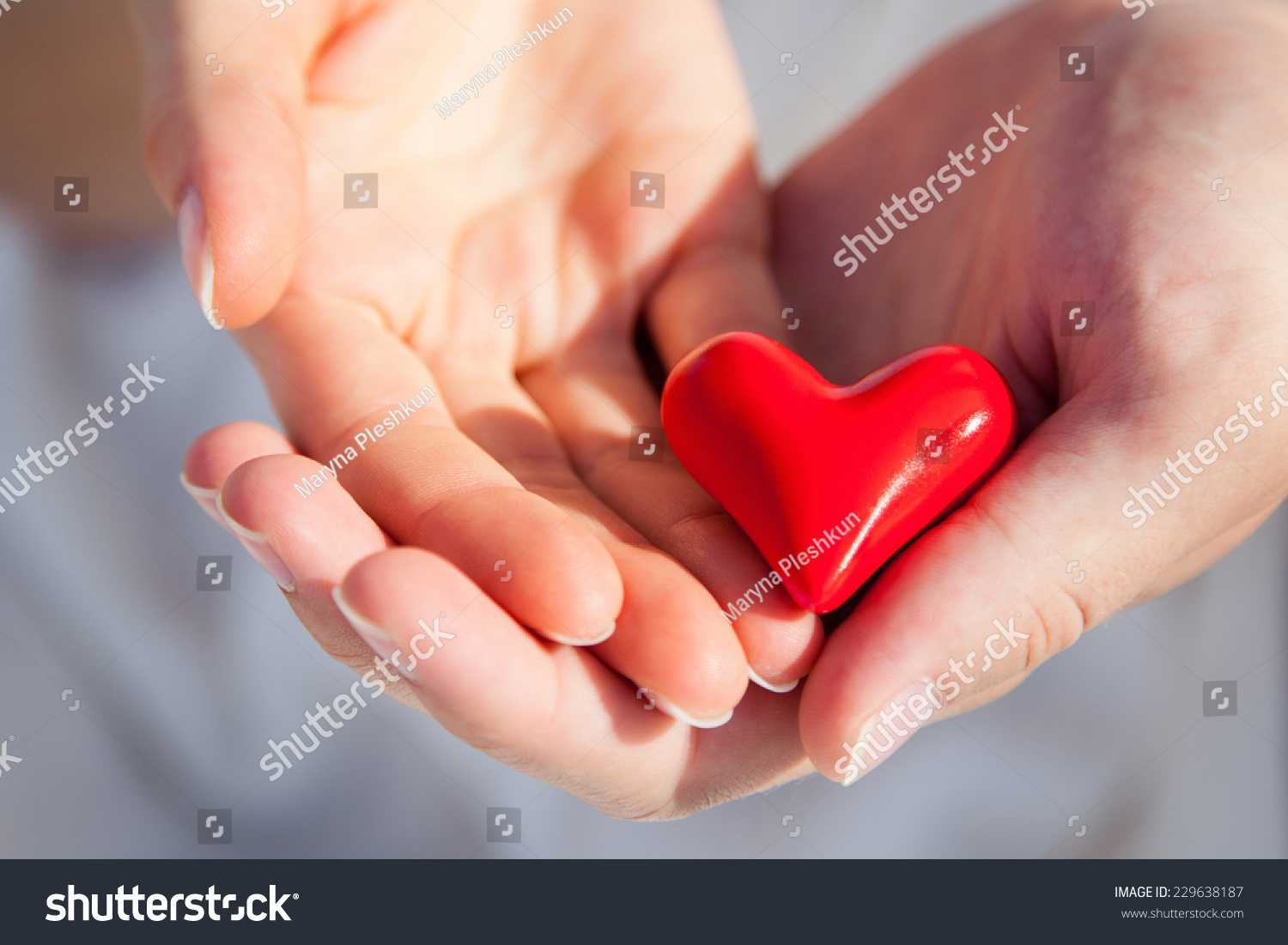 Hands of man and woman holding red heart protecting it together #229638187