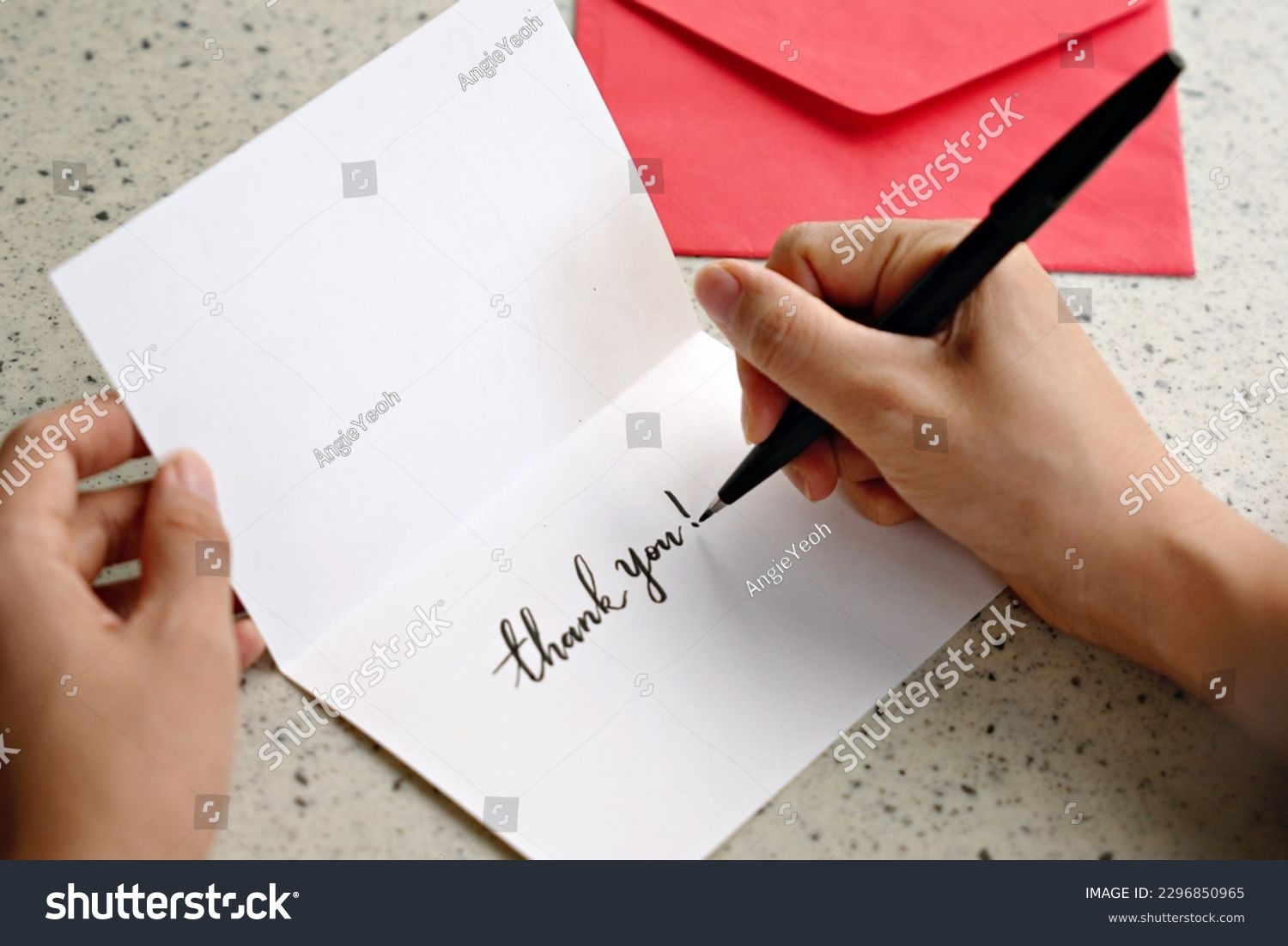 A woman hands writing a Thank You note on a greeting card with red envelope #2296850965