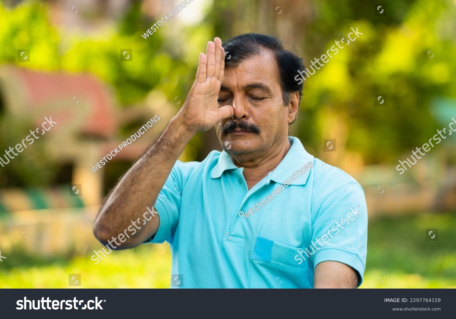 Elderly Indian senior man doing nostril breathing yoga or pranayama exercise - concept of zen, healthy lifestyle and mental wellness #2297764159
