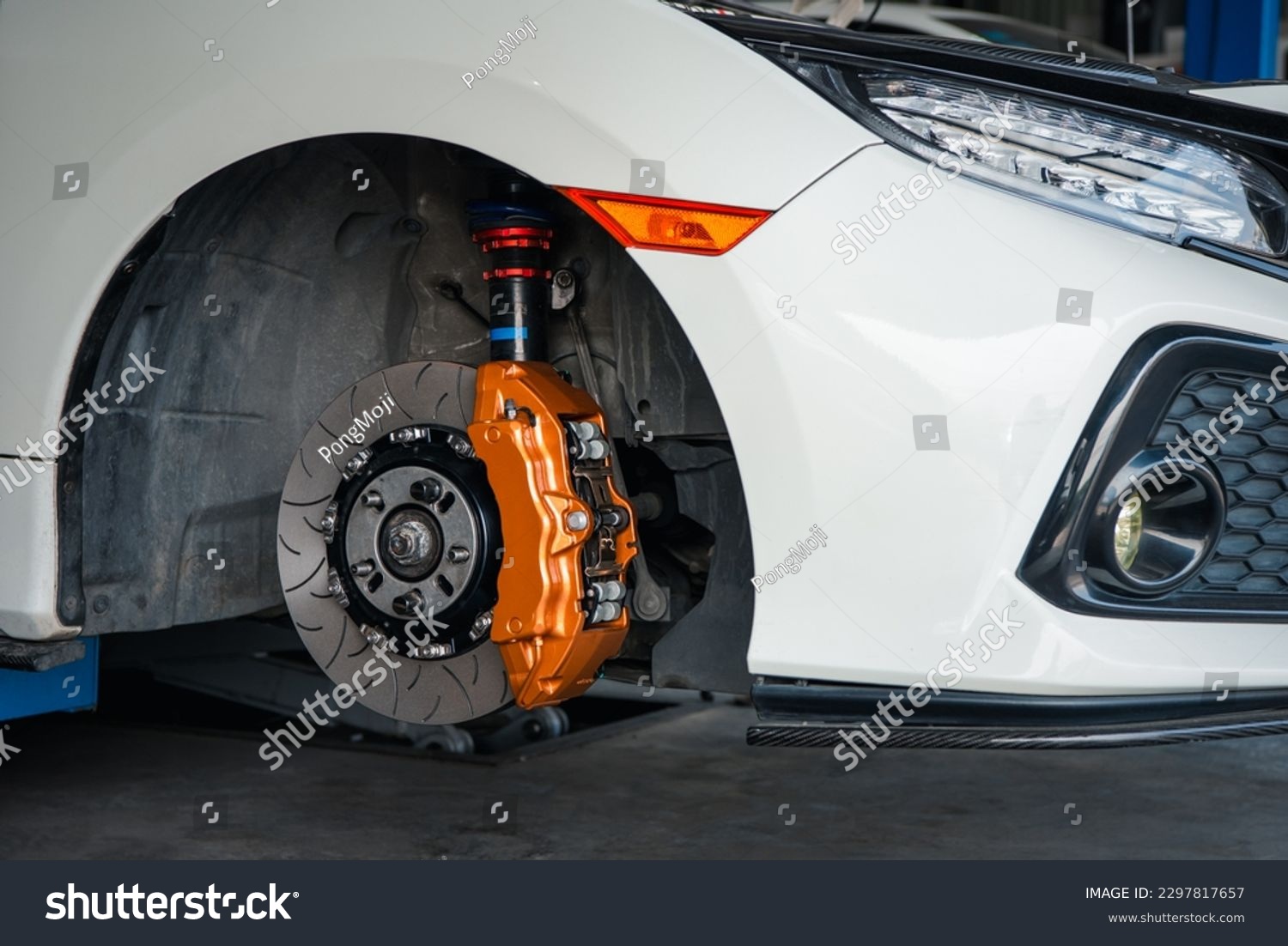 Car mechanic or serviceman disassembly and checking a disc brake and asbestos brake pads for fix and repair problem at car garage or repair shop #2297817657