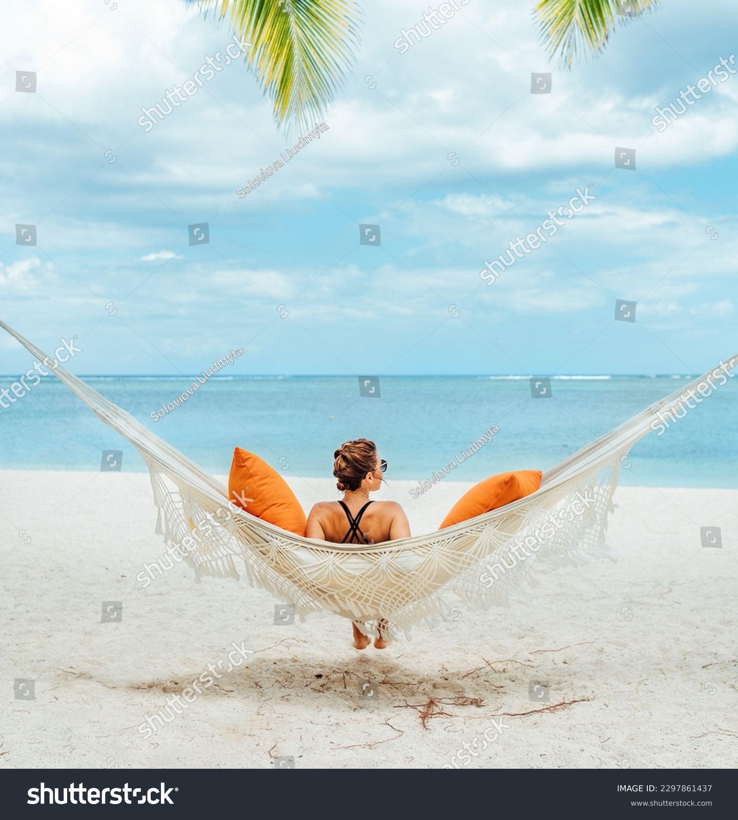 Young woman relaxing in wicker hammock on the sandy beach on Mauritius coast and enjoying wide ocean view waves. Exotic countries vacation and mental health concept image. #2297861437
