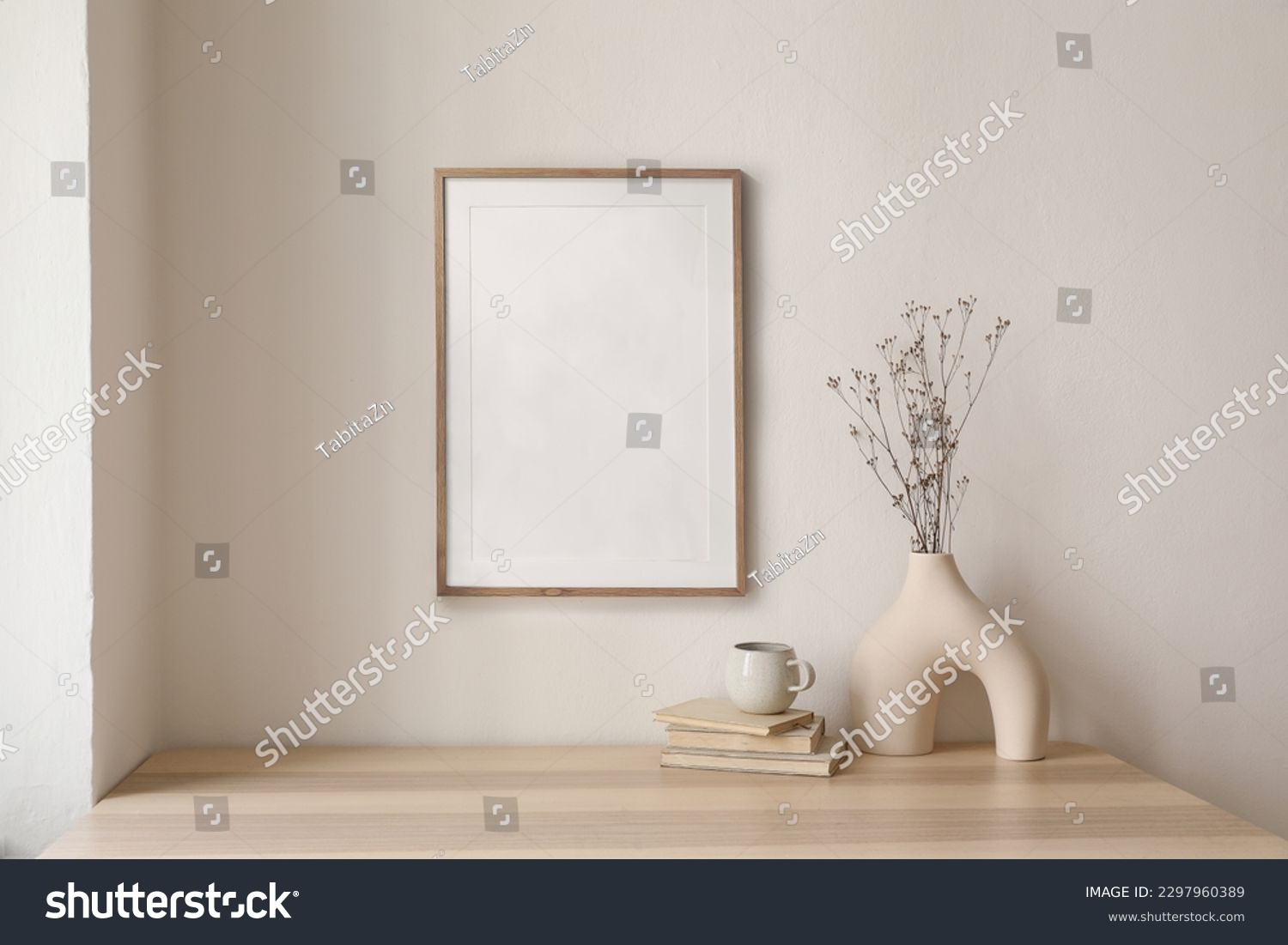 Neutral home still life. Decorative boho interior. Vase with bouquet of dry plants, grass on wooden table. Blank picture frame mockup hanging on wall. White cup of coffee, books. Artistic poster. #2297960389
