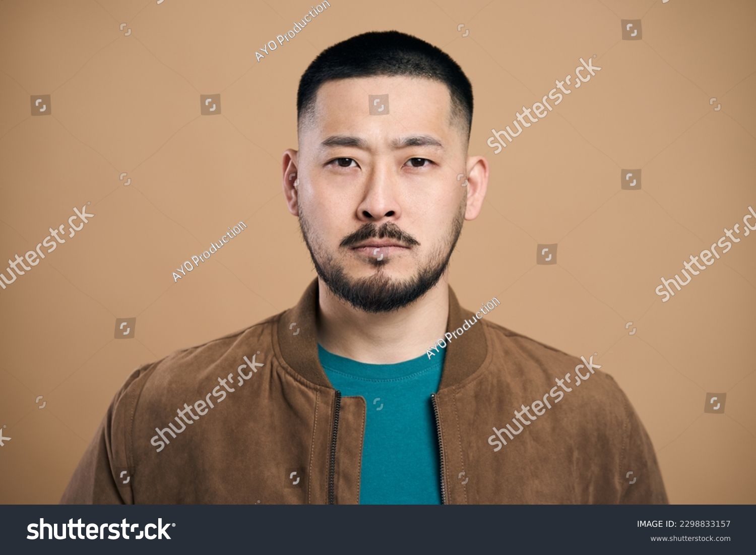 Portrait of self confident bearded asian man looking at camera with serious expression, unsmiling determined business man. Indoor studio shot isolated on brown background  #2298833157