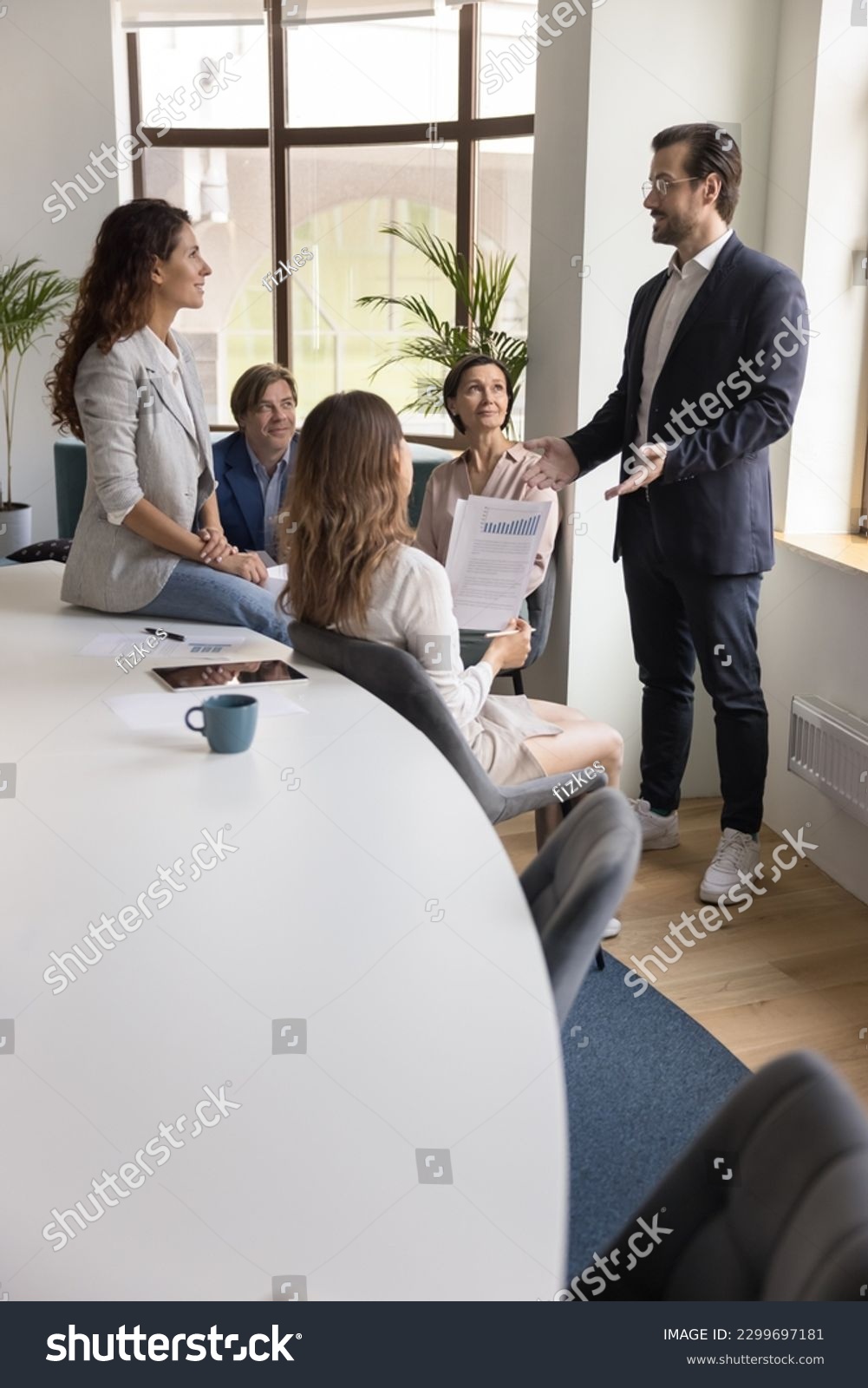 Confident businessman, male boss in suit explains new project details, share business strategy, makes speech stand in front of company staff members during corporate group briefing in conference room #2299697181