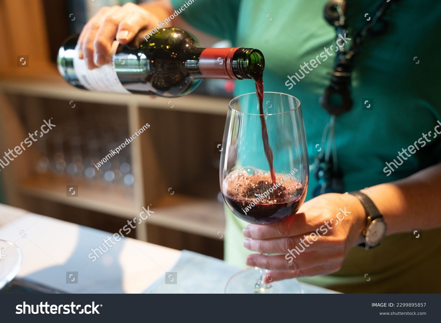 Woman pooring glass of red wine  #2299895857