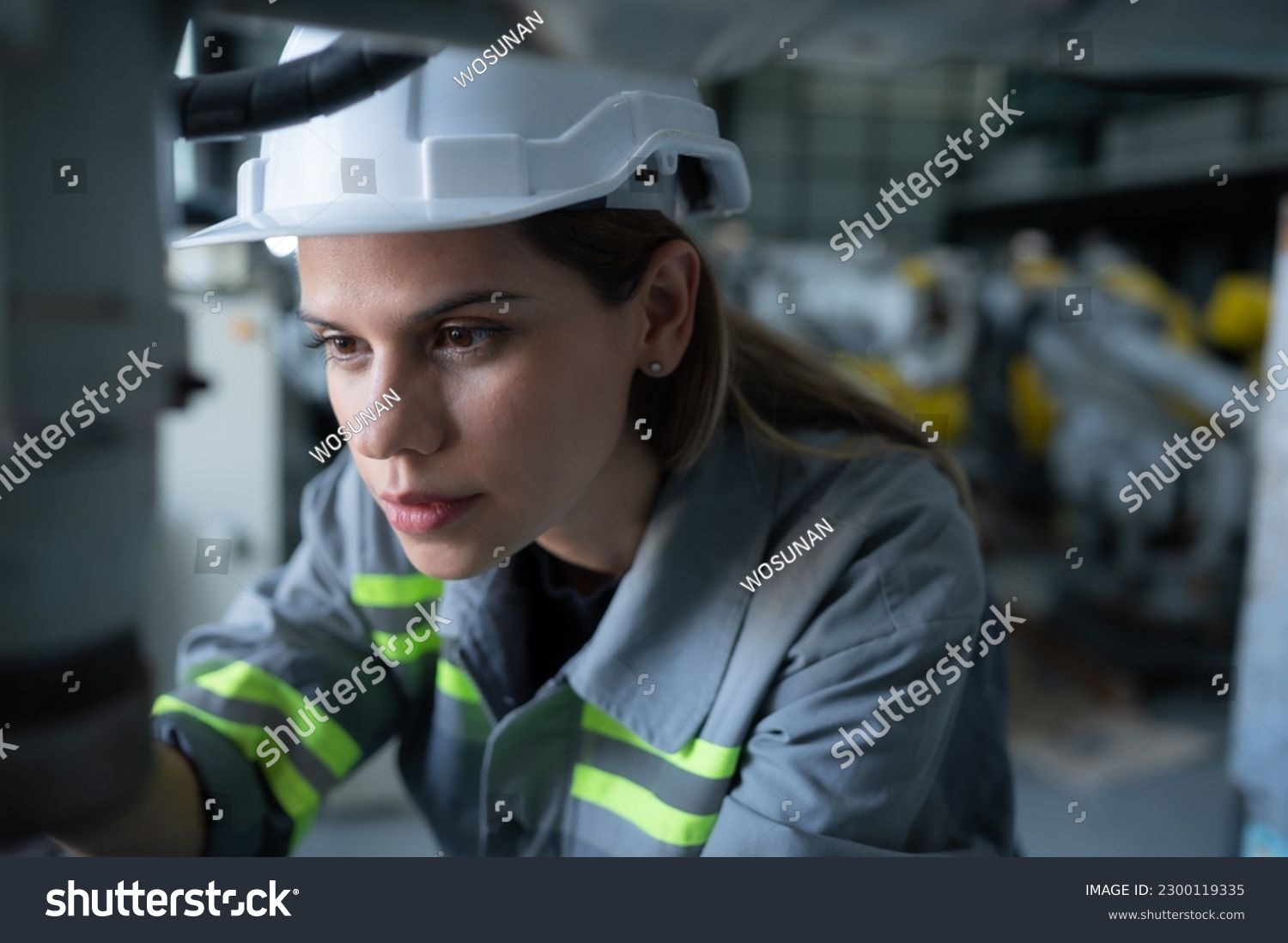 Female Technician Inspecting and repairing robotics arm in robots hangar and test the operation of the machine after being used for a while, as well as updating the software and calibration #2300119335