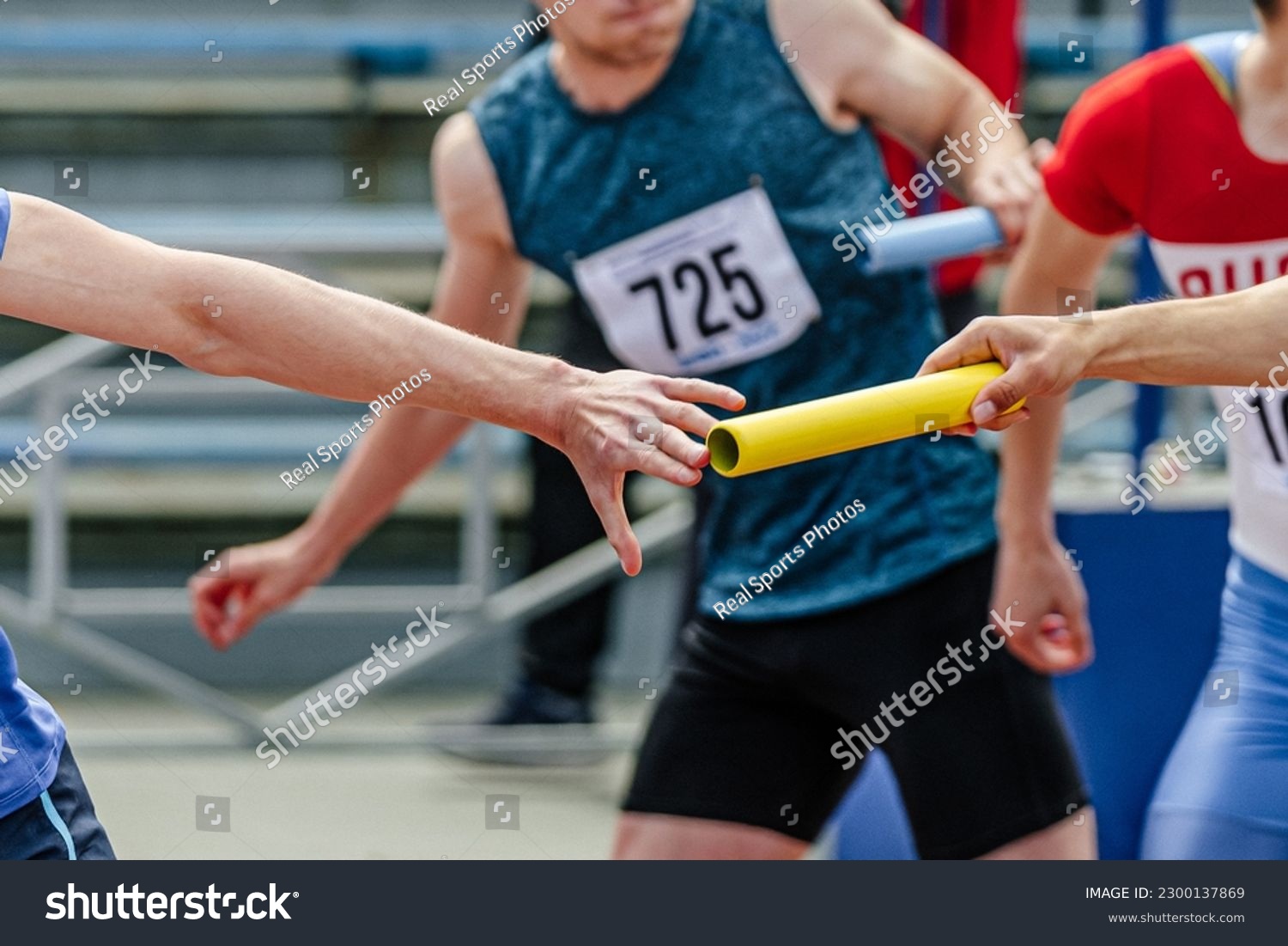 men relay race baton passing in summer athletics championship, close-up of athletes hands on background of runners #2300137869