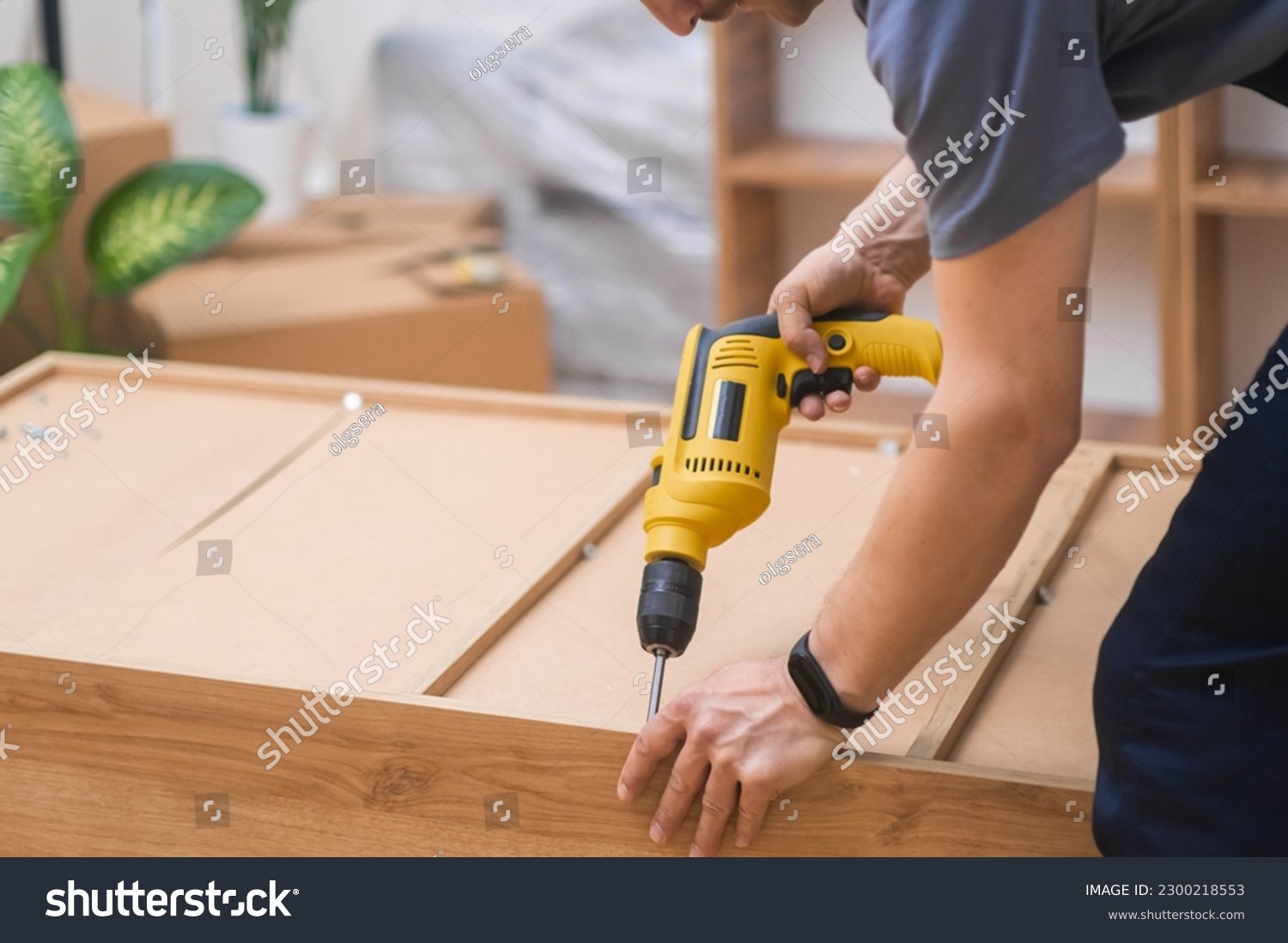 Custom furniture assembling handyman fixing fasteners on wooden cabinet back side with professional screwdriver quality carpentry services specialist working with wood materials #2300218553