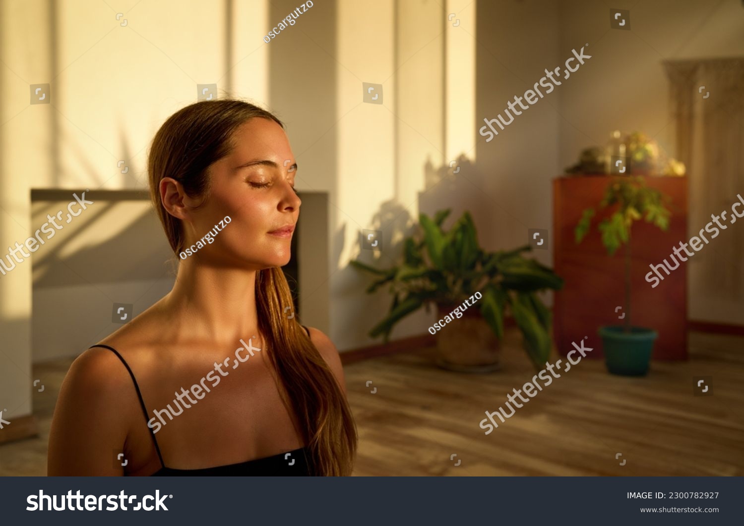 portrait young caucasian woman sitting with closed eyes meditating indoors #2300782927
