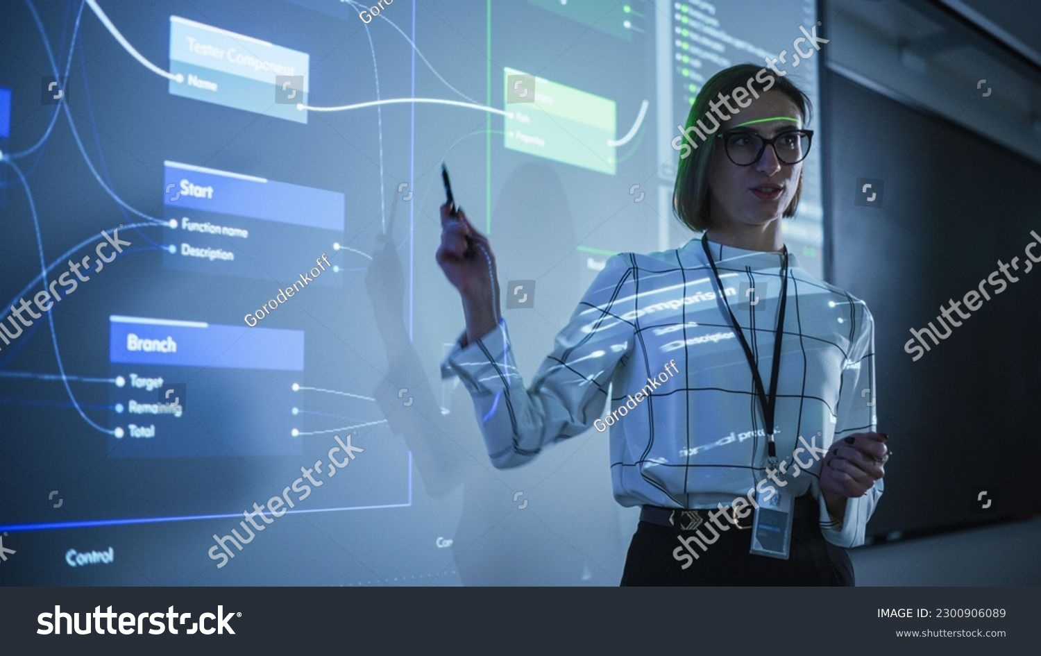 Portrait of a Young Female Professor Explaining Big Data and Artificial Intelligence Research Project in a Dark Room with a Screen Showing a Neural Network Model. Computer Science Education in College #2300906089