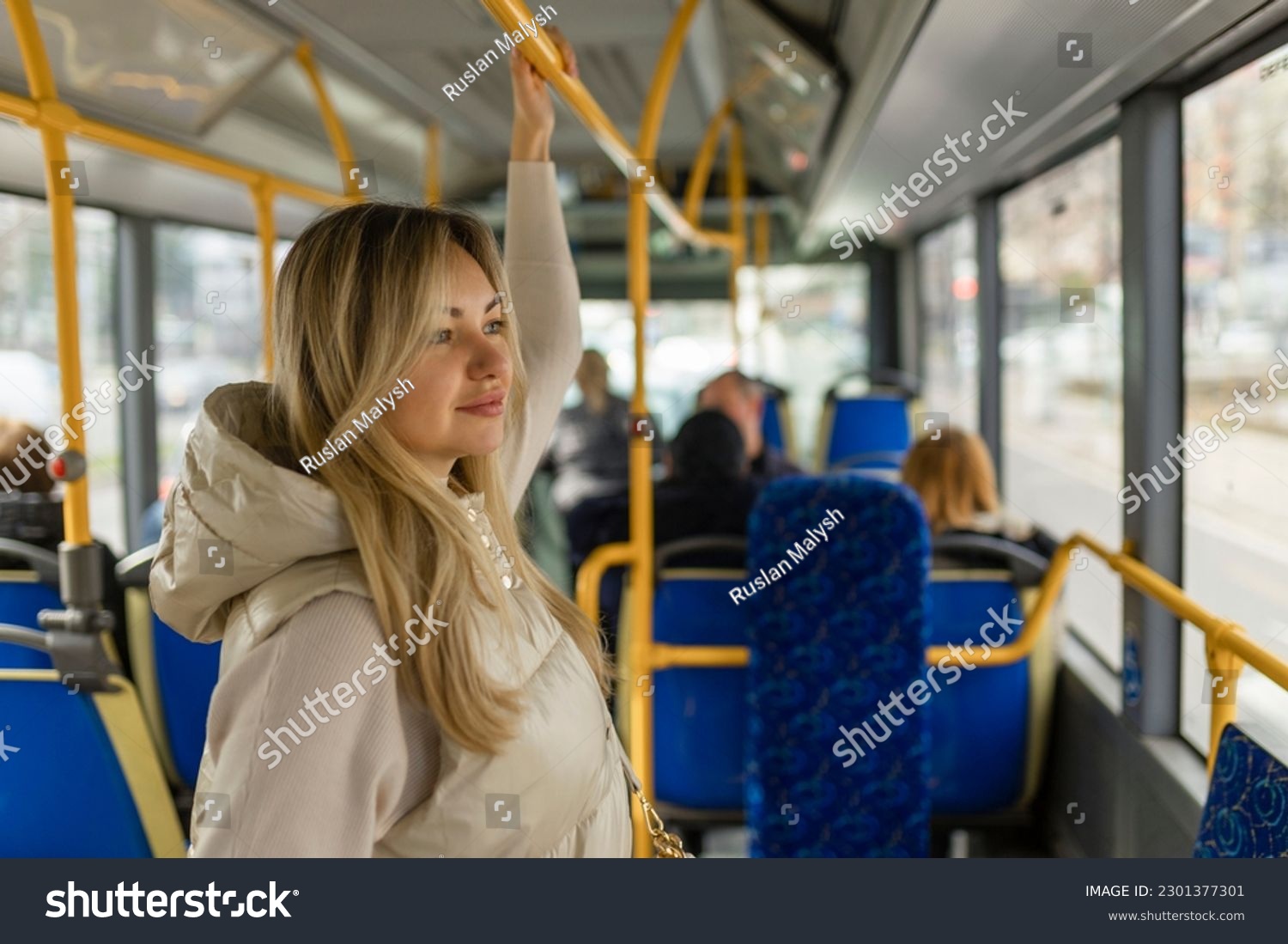 Beautiful young adult caucasian woman stands in the bus and looks into the distance #2301377301