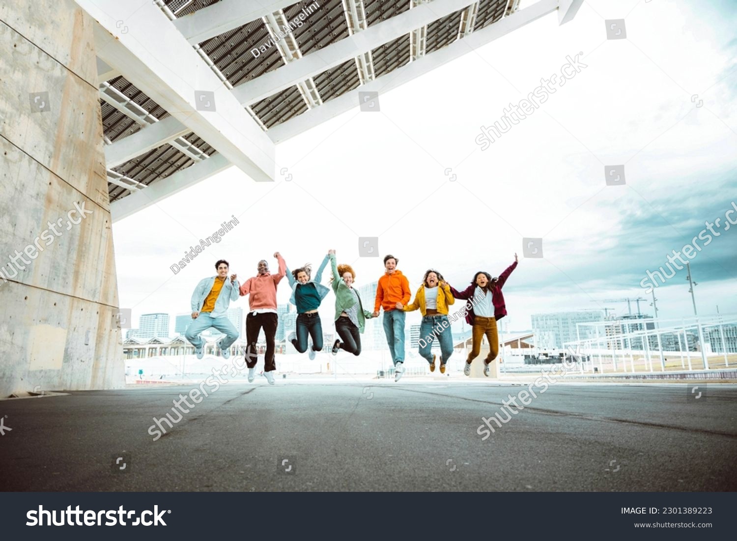 Happy group of young people jumping on city street - Multiracial students college celebrating outside - Life style concept with guys and girls having fun together hanging outside #2301389223