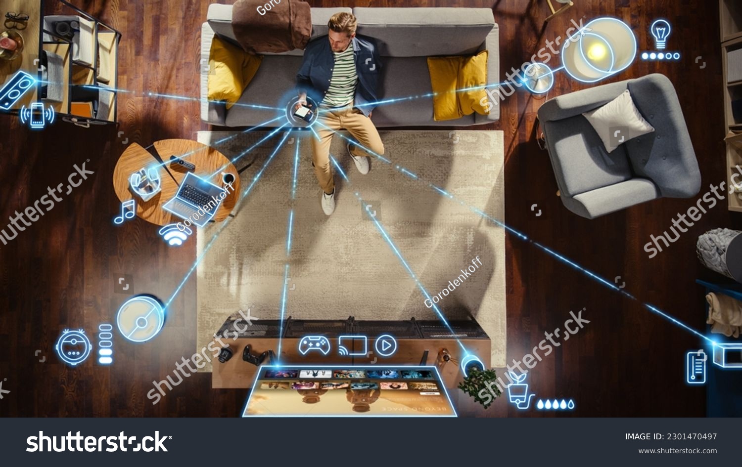 Top View Of Caucasian Man In the Loft Apartment Sitting Down on The Couch and Connecting Smartphone to Convenient Smart Home System. VFX Edit Visualizing Connected Devices. Laptop, TV, Speaker. #2301470497