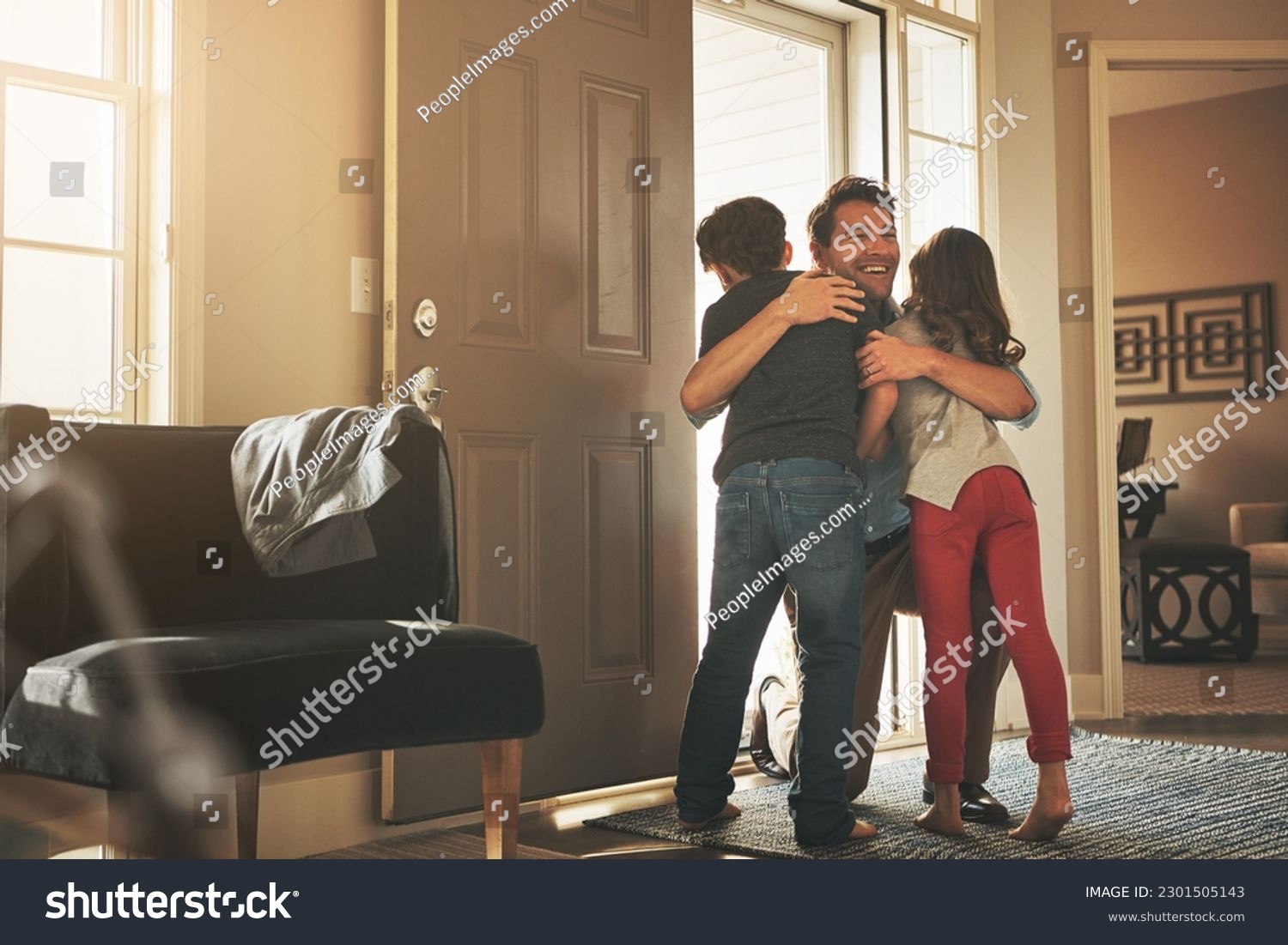 Home, love and a father hugging his kids after arriving through the front door after work during the day. Greeting, family or children with a man holding his son and daughter in the living room #2301505143