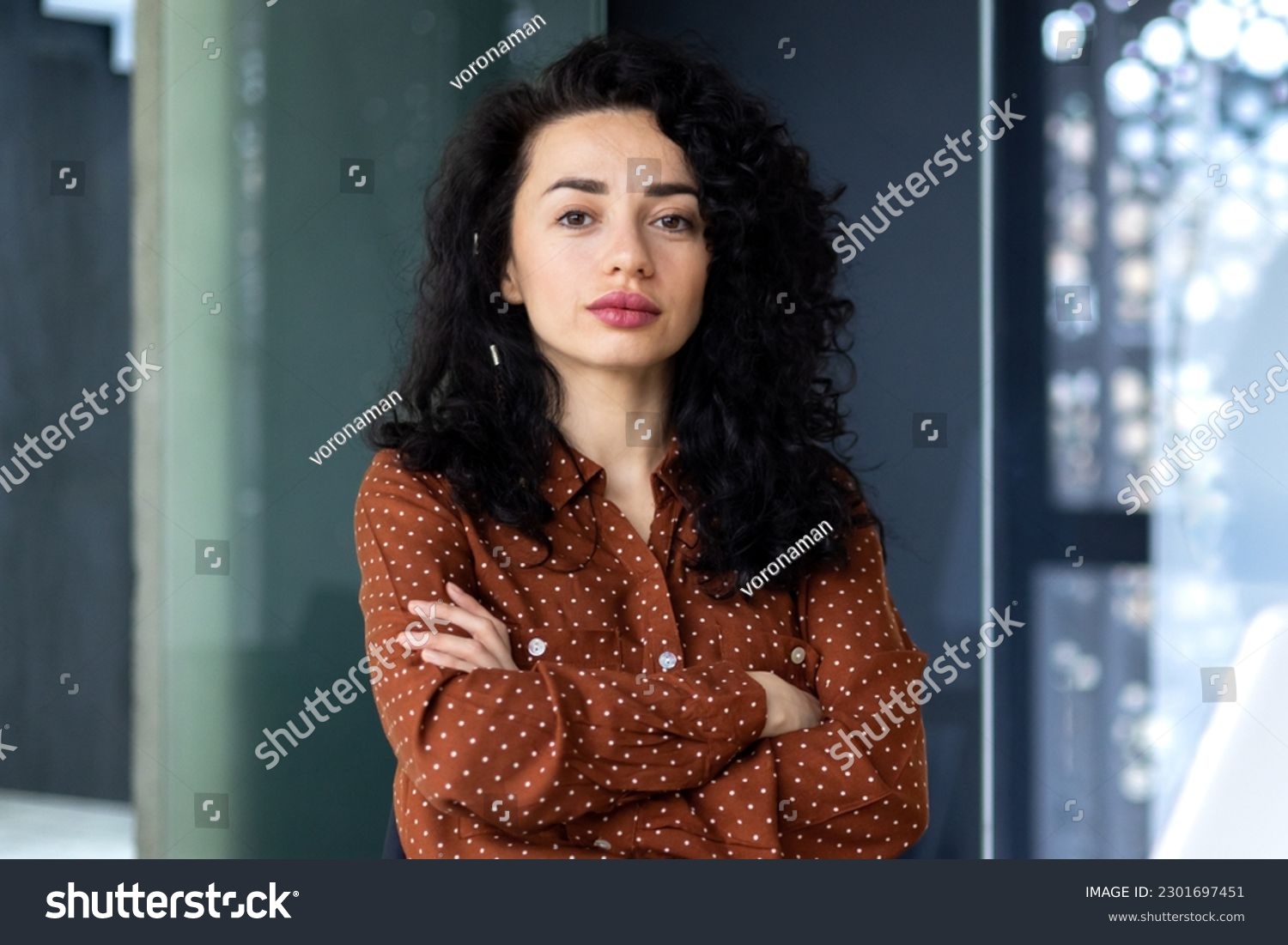 Portrait of mature female boss inside office building, successful hispanic woman looking serious at camera with crossed arms, businesswoman confident. #2301697451