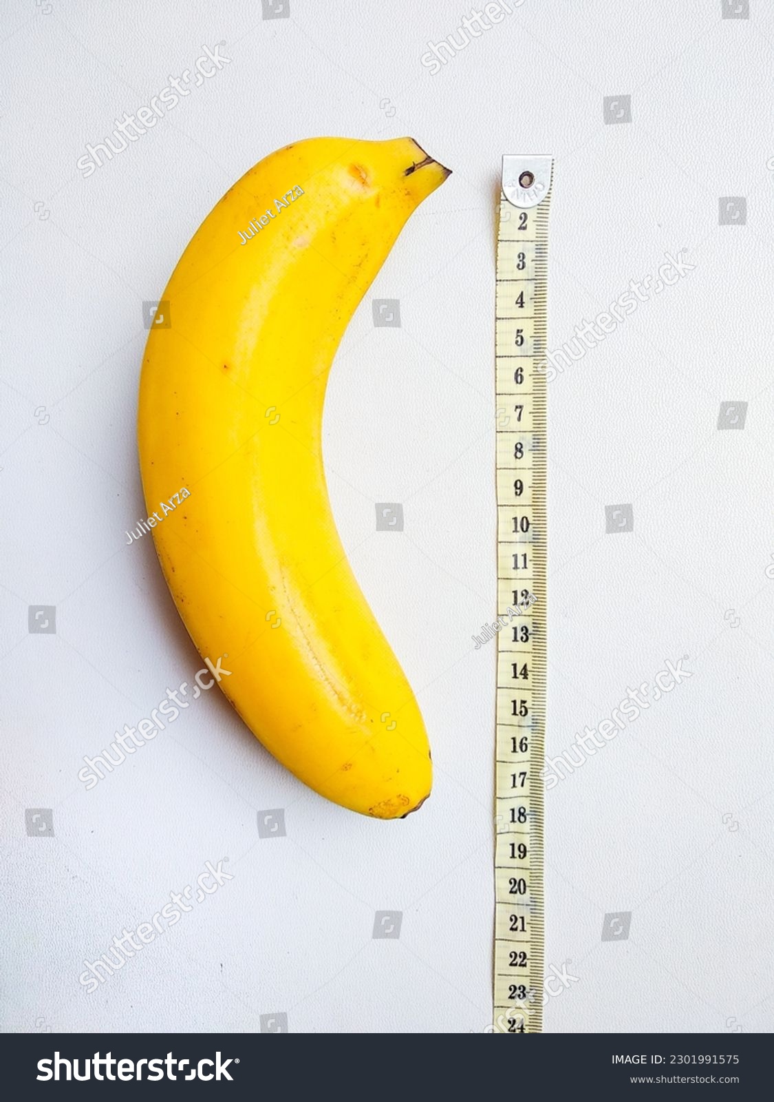 Yellow banana with measurement tape on white background. Male genitalia size concept #2301991575