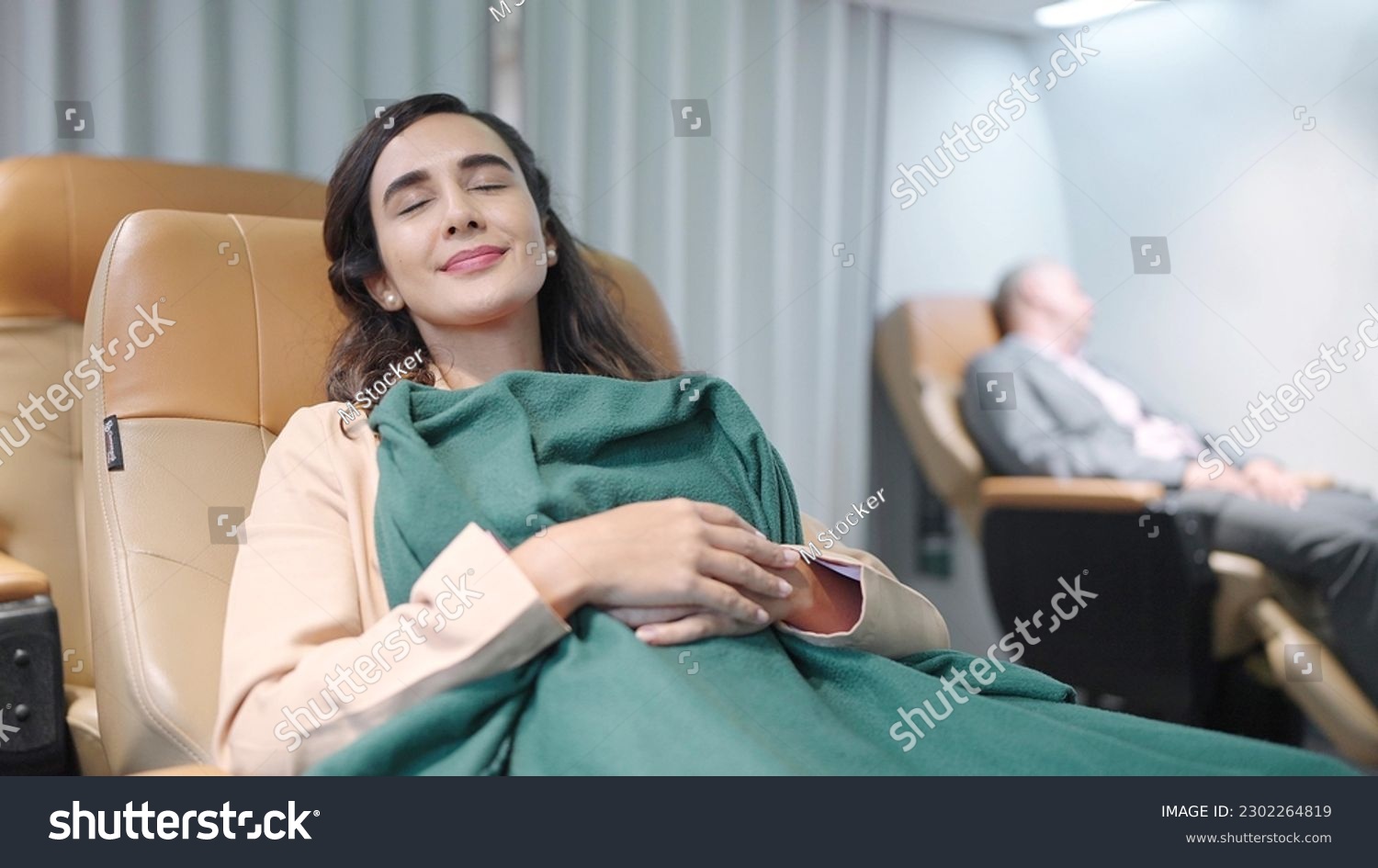 Young Hispanic latino woman passenger sleeping on seat with blanket while traveling by airplane. Woman travel on long flight #2302264819