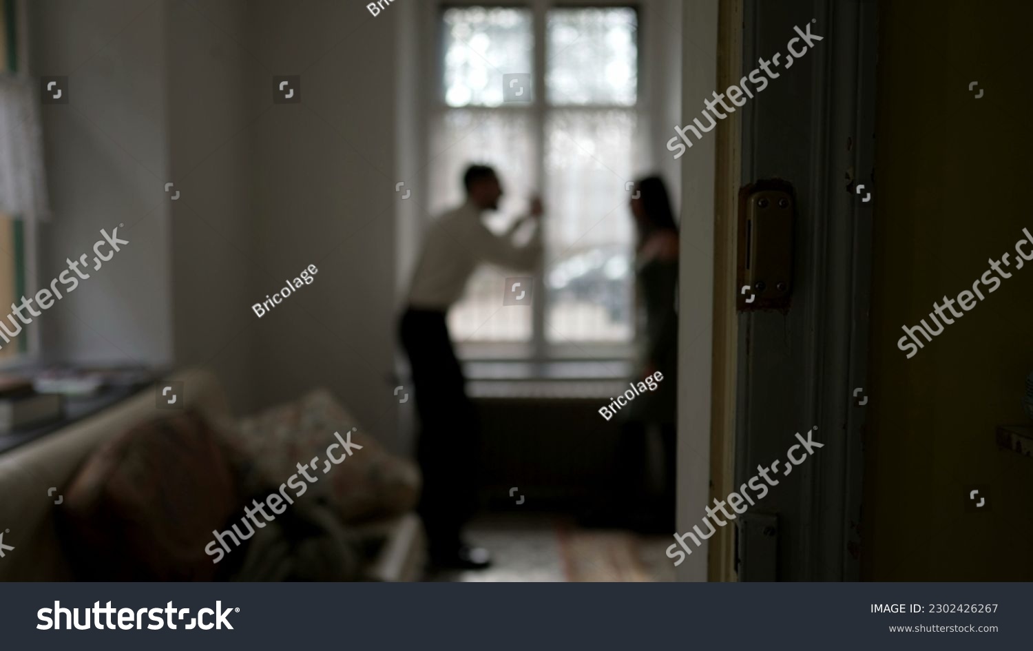 Blurred shot of couple arguing at home. Candid moment of husband and wife fighting each other. Person threatening the other in discussion #2302426267