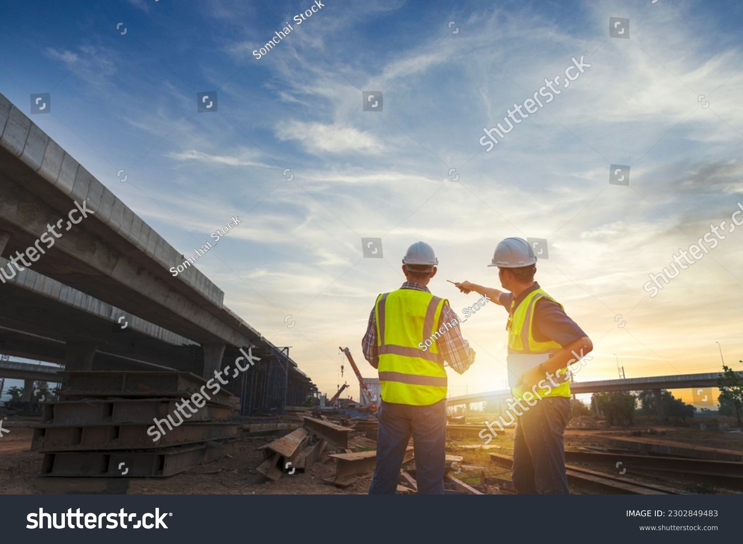 Asian architect and mature supervisors meeting at construction site Multiethnic workers and engineers discussing plans Two construction workers working together while visiting expressway construction #2302849483
