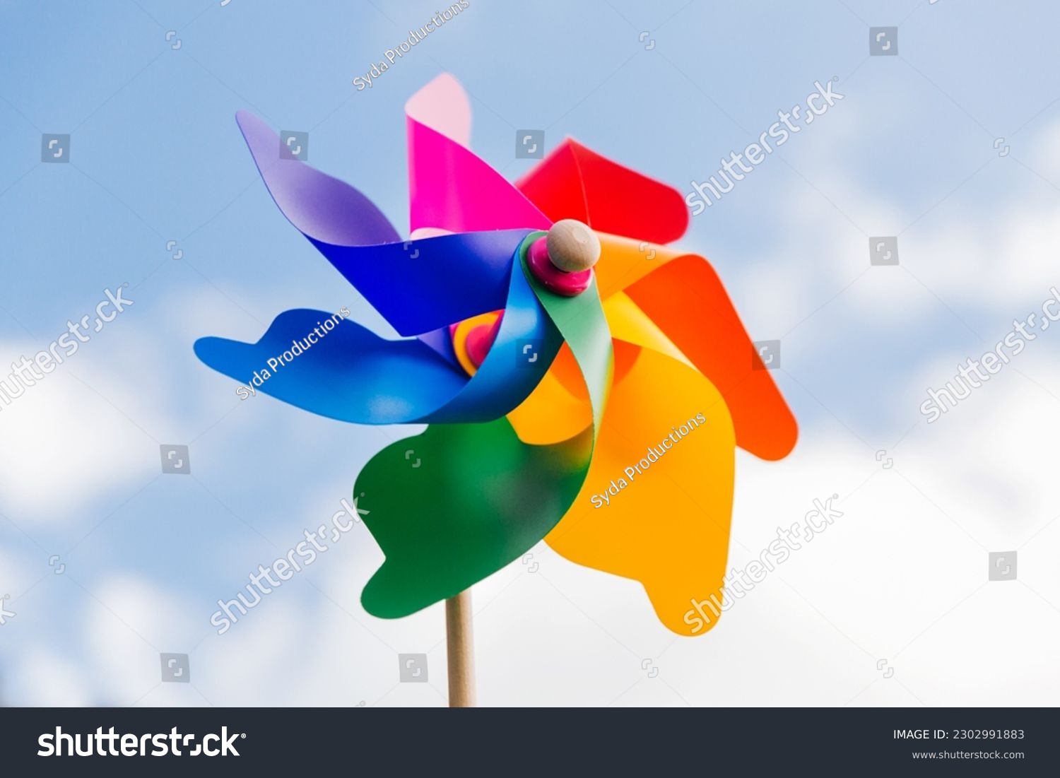 ecology, environment and sustainable energy concept - close up of multicolored pinwheel over blue sky #2302991883