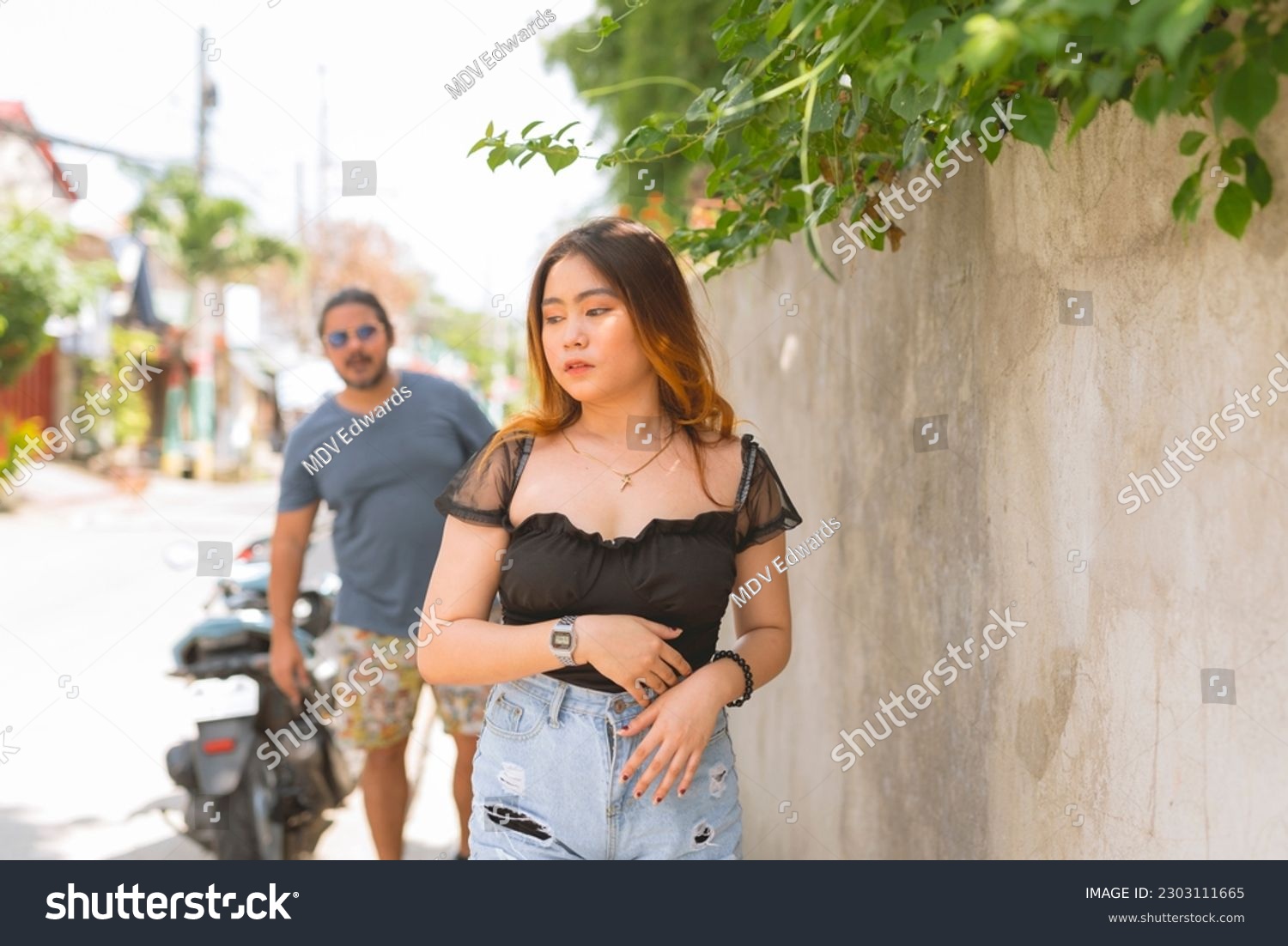 An anxious asian woman notices a creepy man following her for a while. Outdoor scene. #2303111665
