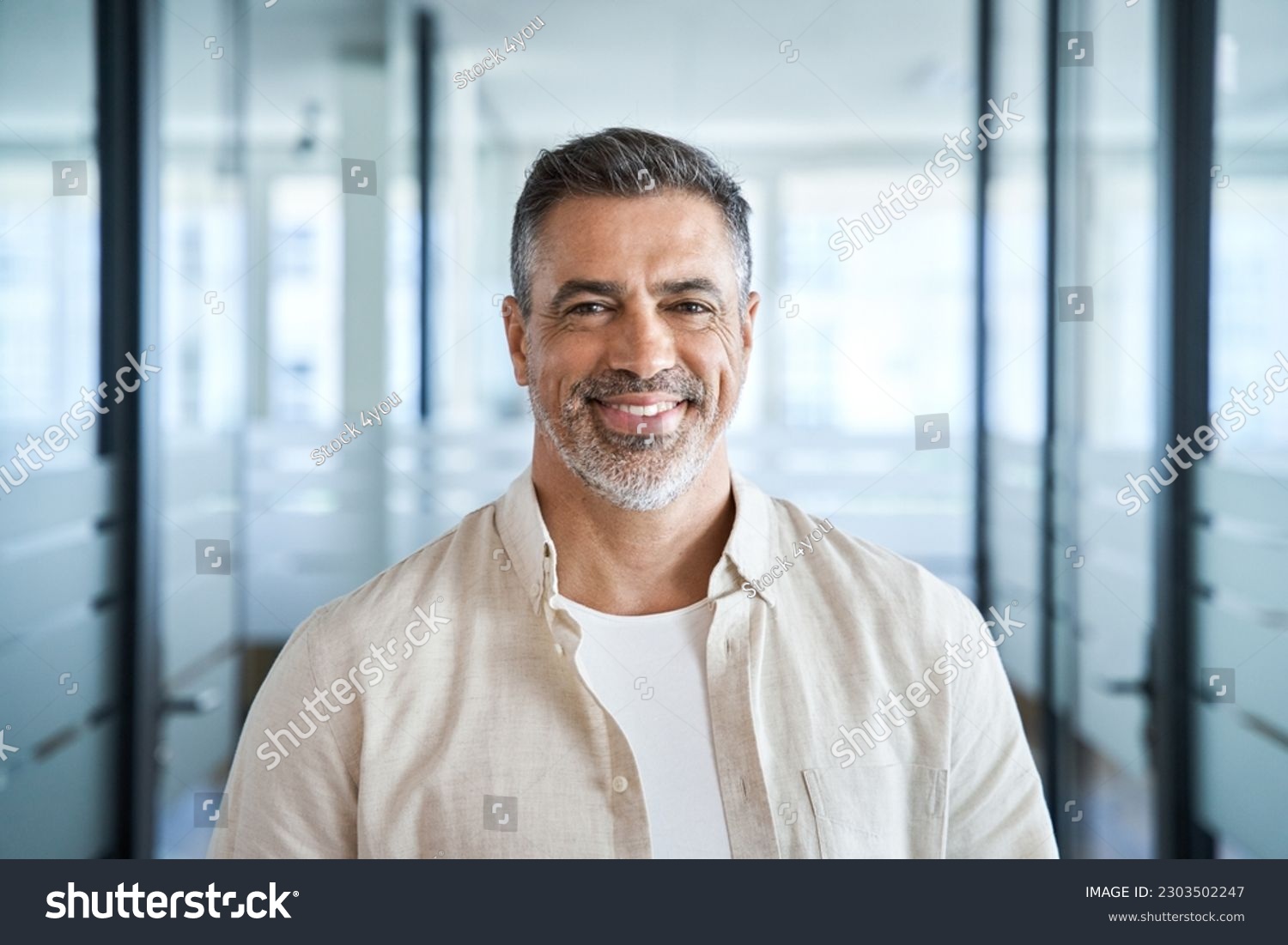 Headshot close up portrait of indian or latin confident mature good looking middle age leader, ceo male businessman on blur office background. Handsome hispanic senior business man smiling at camera. #2303502247