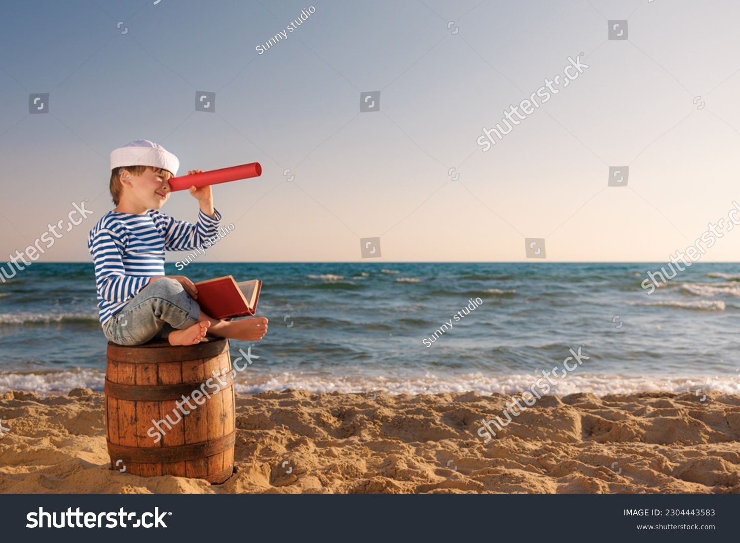Child pretend to be sailor. Kid looking through spyglass. Child sitting on old barrel on the beach. Boy on summer vacation. Adventure and travel concept #2304443583