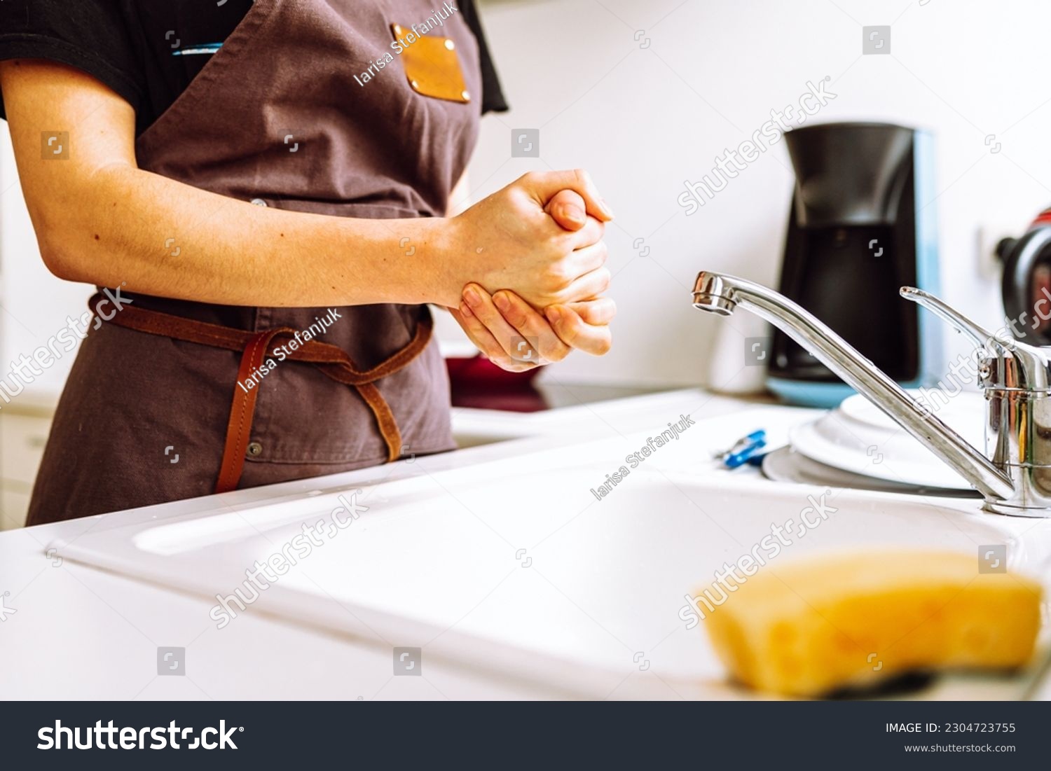 female slender figure in chef's work apron stands near kitchen sink, hands housewife dishwasher after washing dishes #2304723755