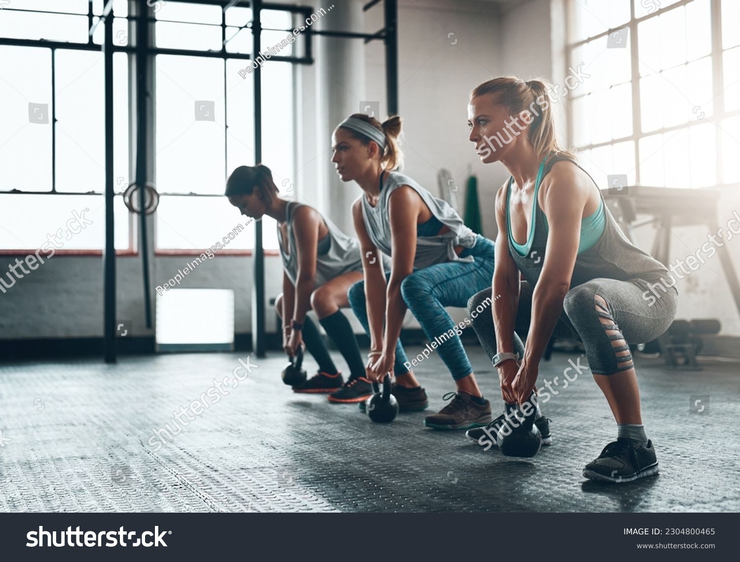 Kettlebell, fitness and women in a gym, training or workout goal with wellness, class or exercise. Female athlete, girls or squat with equipment, sports or relax with healthy lifestyle or challenge #2304800465
