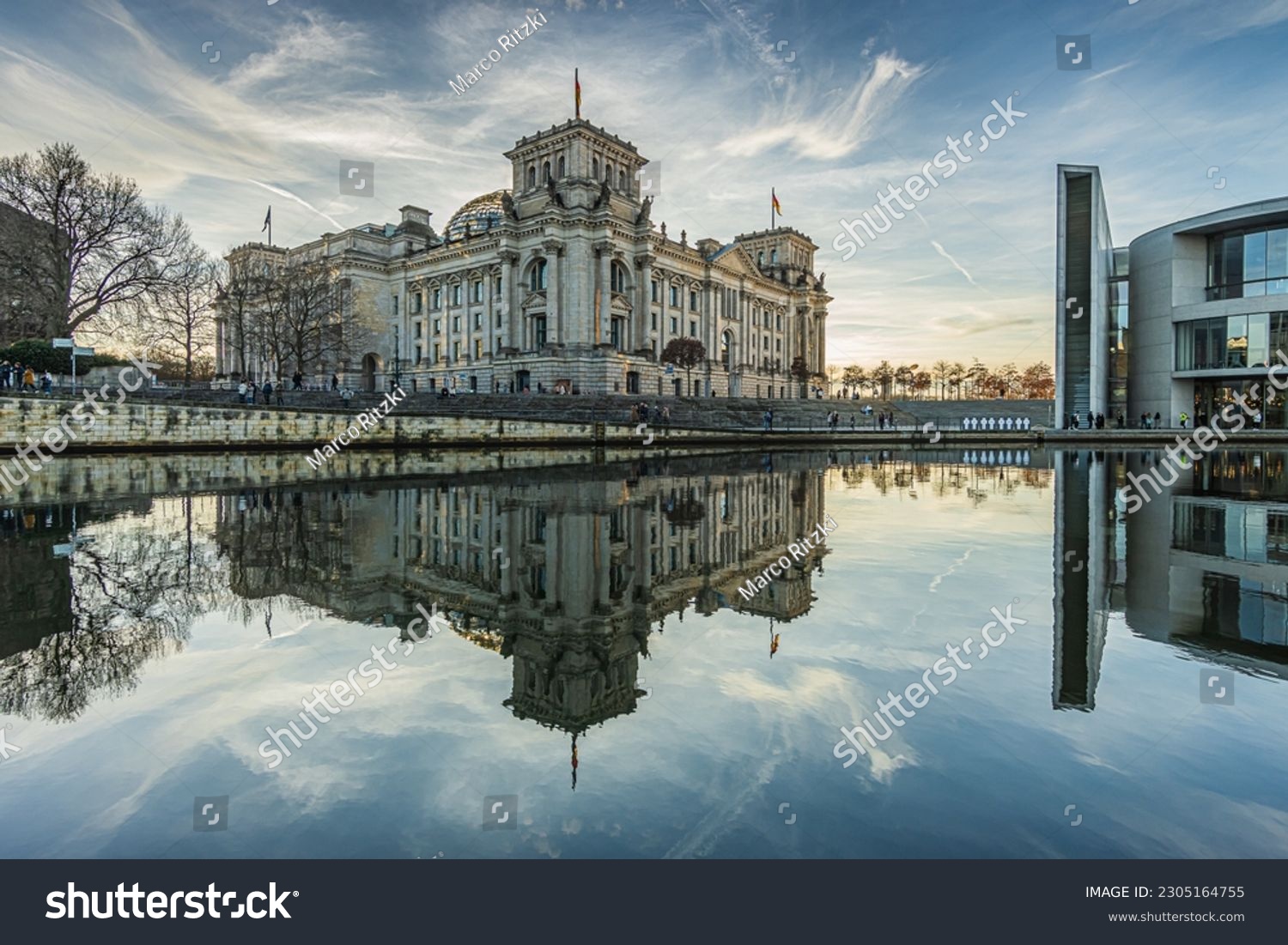 historic Reichstag building in Berlin during the day in winter. River Spree with reflection from the building in the government district. Sunshine in the background with cloudy skies. #2305164755