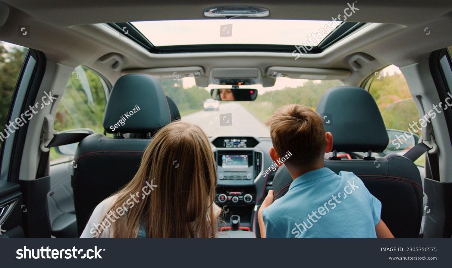 Rear view. Children boy and girl sitting in back seat of car during family trip. Happy family is driving a modern car #2305350575