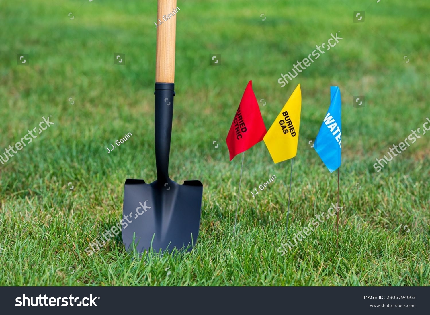 Buried electric, natural gas and water utility warning flag with shovel. Notify utility locate company for underground utilities, call before you dig and digging safety concept #2305794663