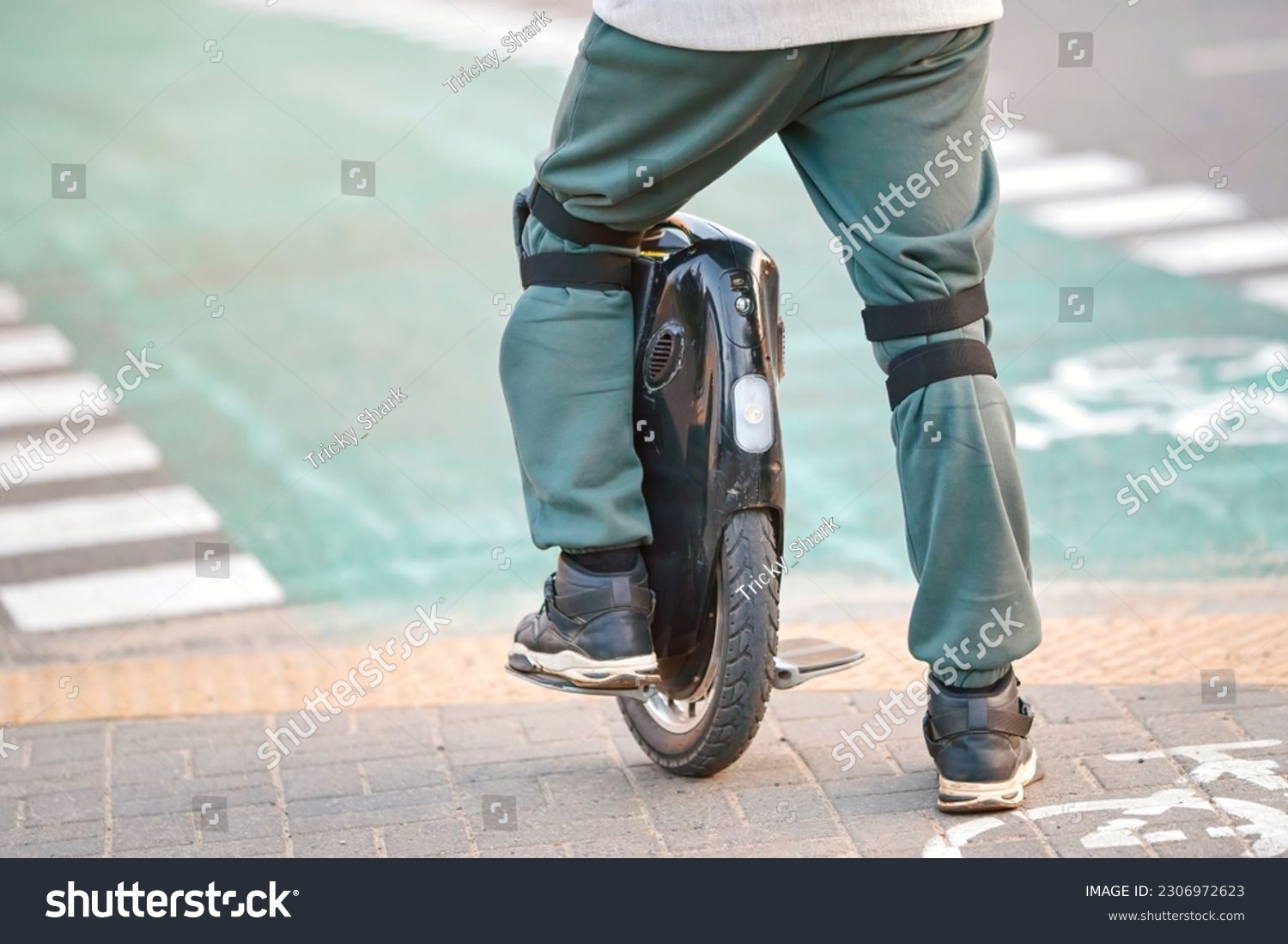 Man in protective gear on electric mono wheel waiting on crosswalk. Man on electric single wheel on crosswalk, rear view. Mobile portable individual transportation vehicle (EUC) #2306972623